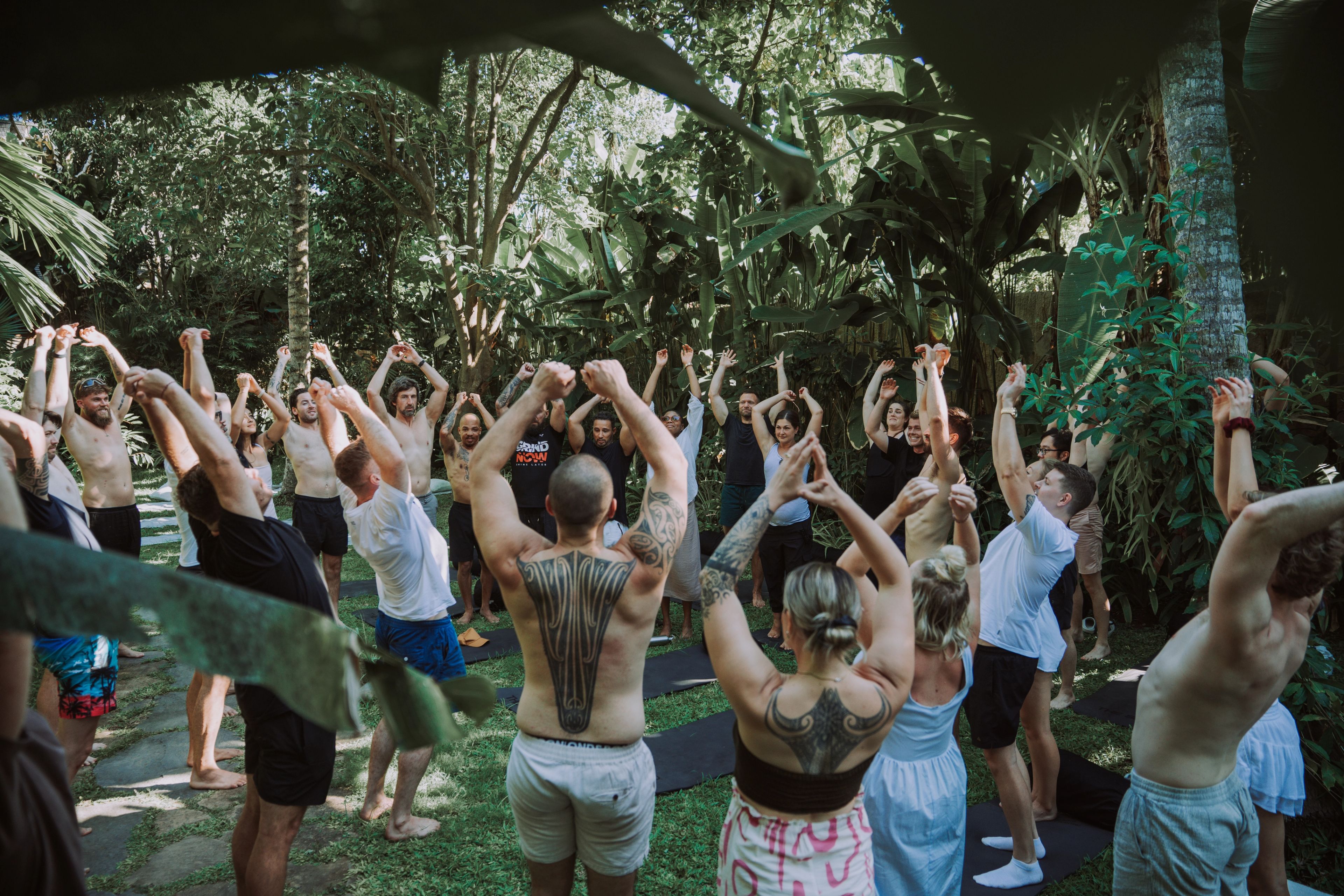 Group of guests stretching arms overhead in a circle surrounded by jungle