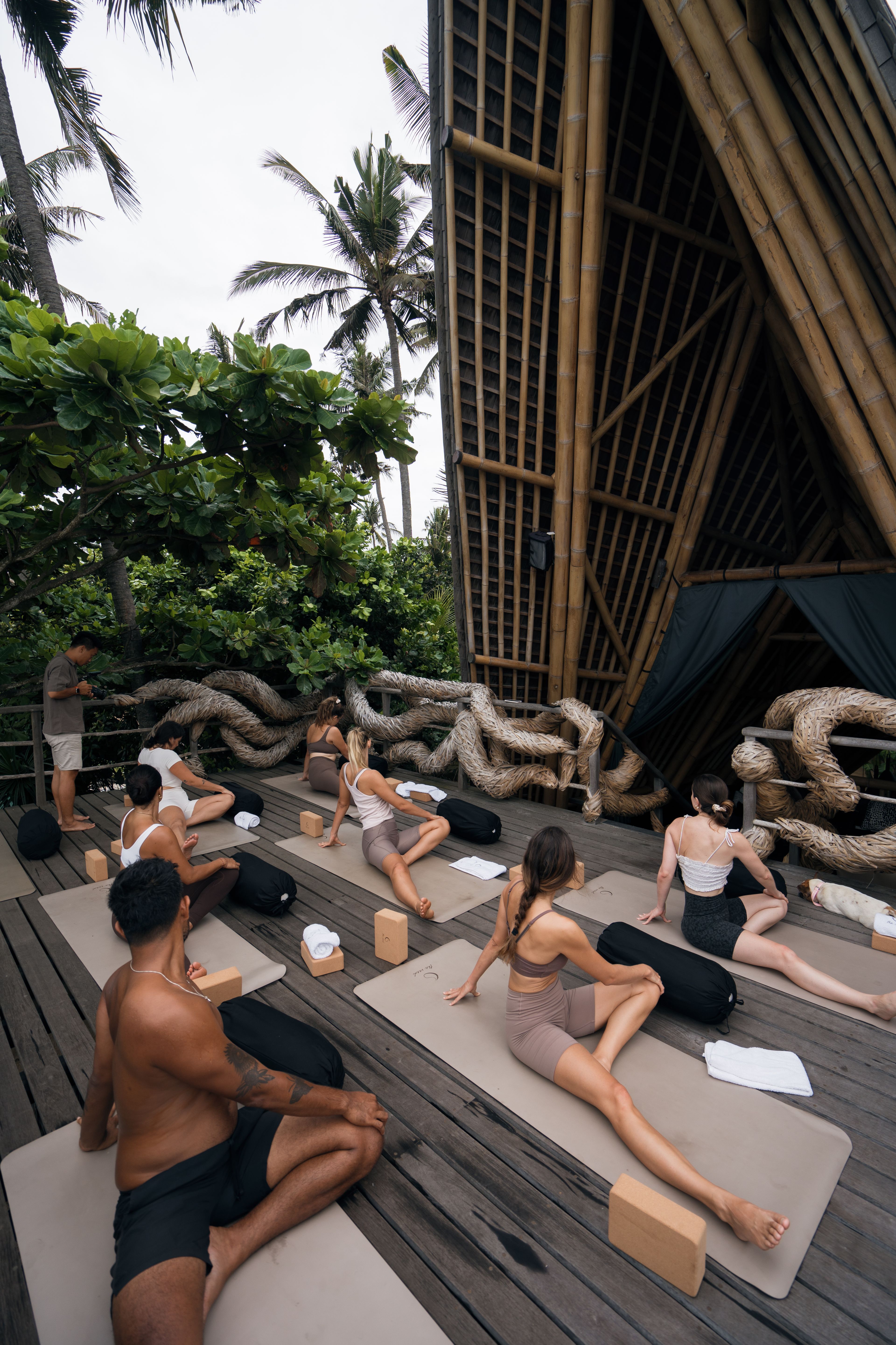 Guests in a seated stretch on their mats while the teacher moves between them.
