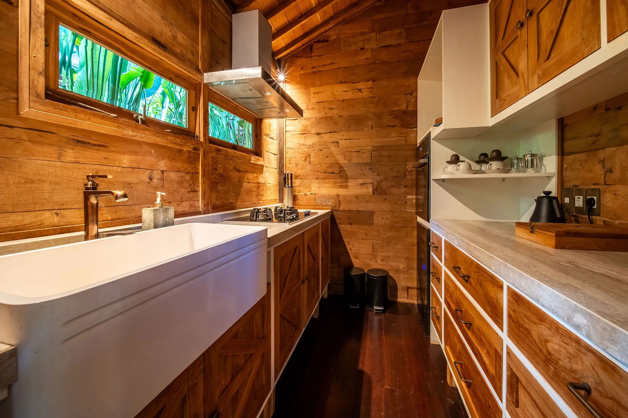 The timber-lined prep kitchen with a deep farmhouse sink, counters and stained-glass windows.