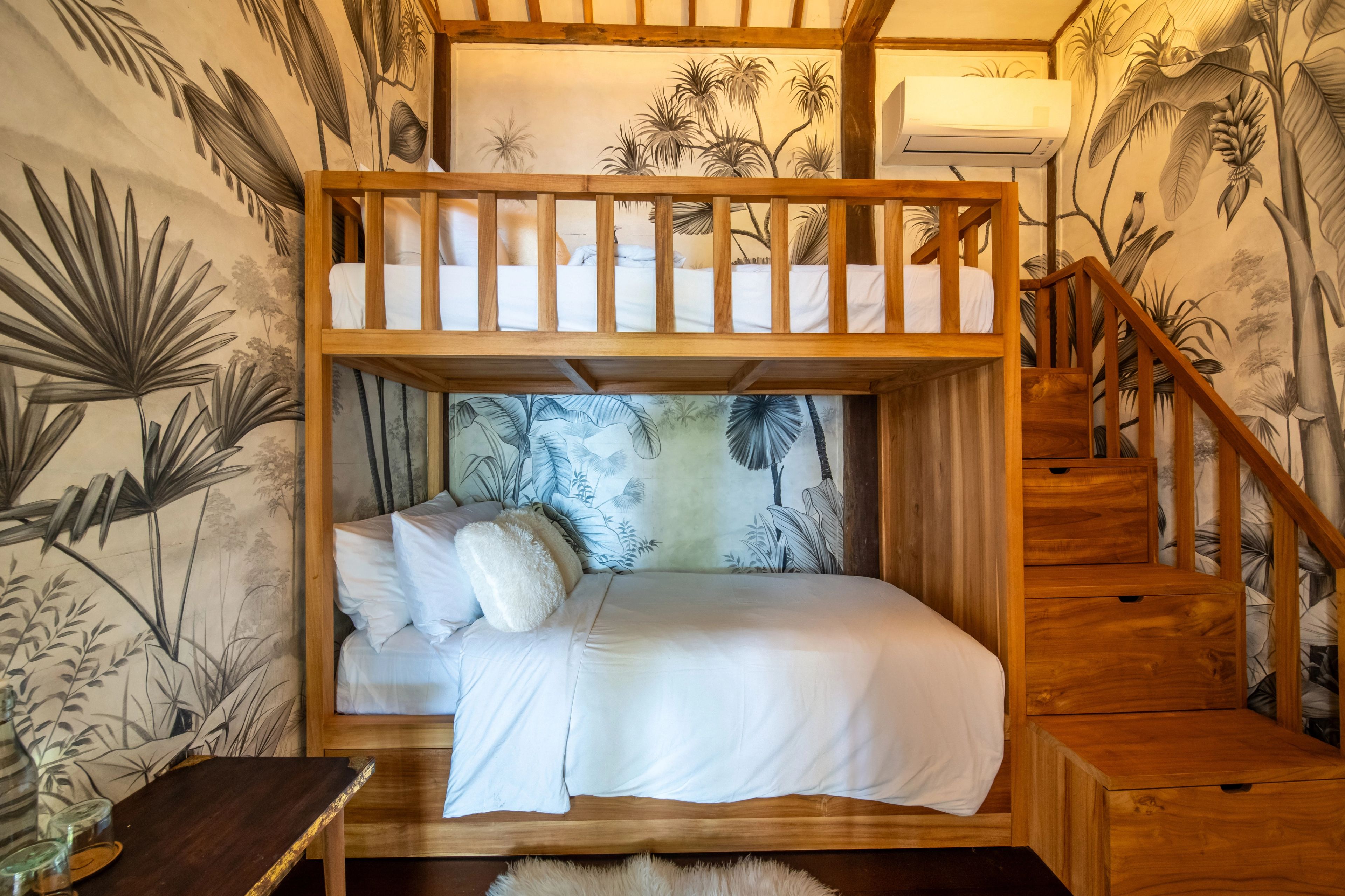 The bunk beds seen from the doorway, palm-print wallpaper running around the room.