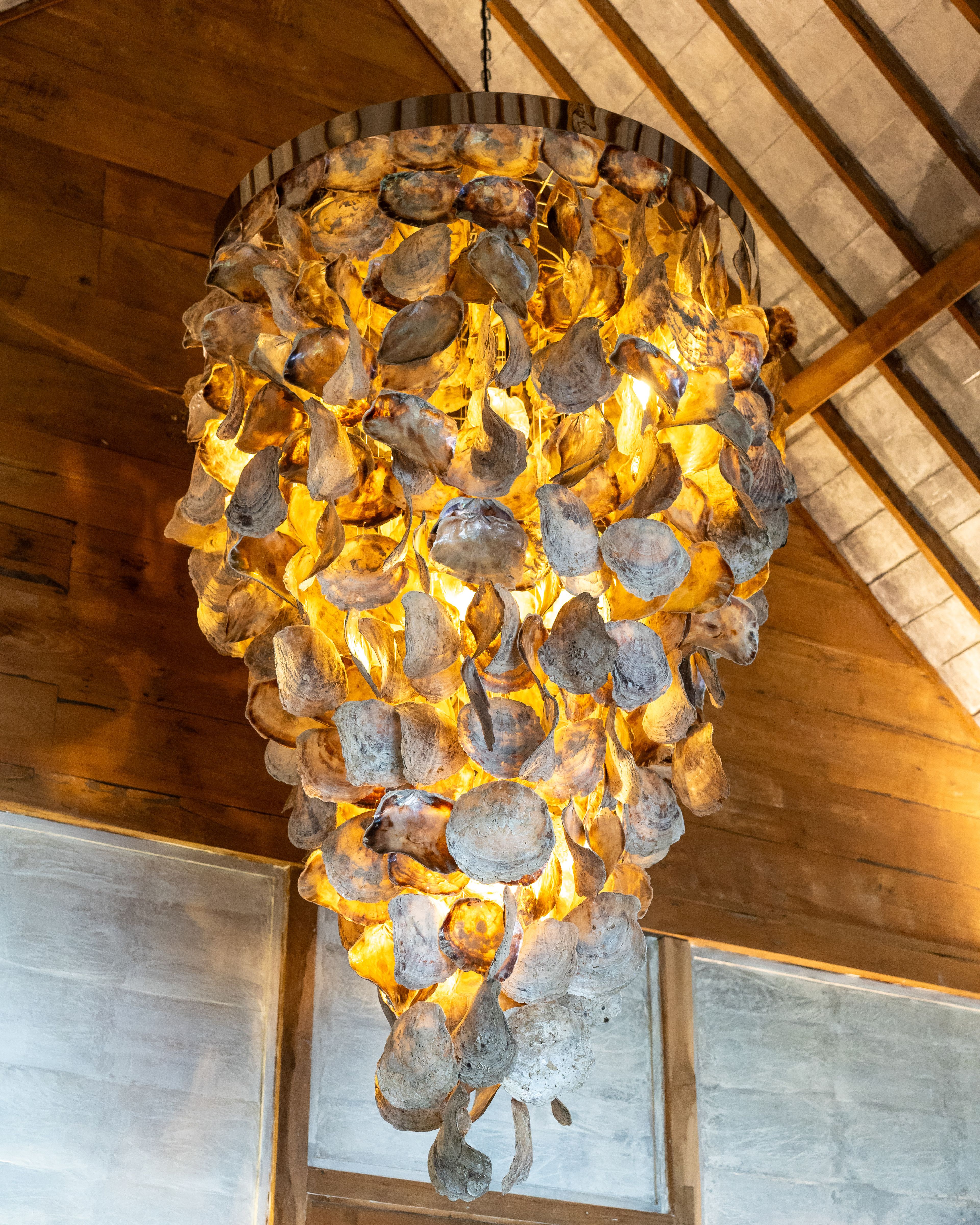 A chandelier of clustered shells lit warm against the timber ceiling.