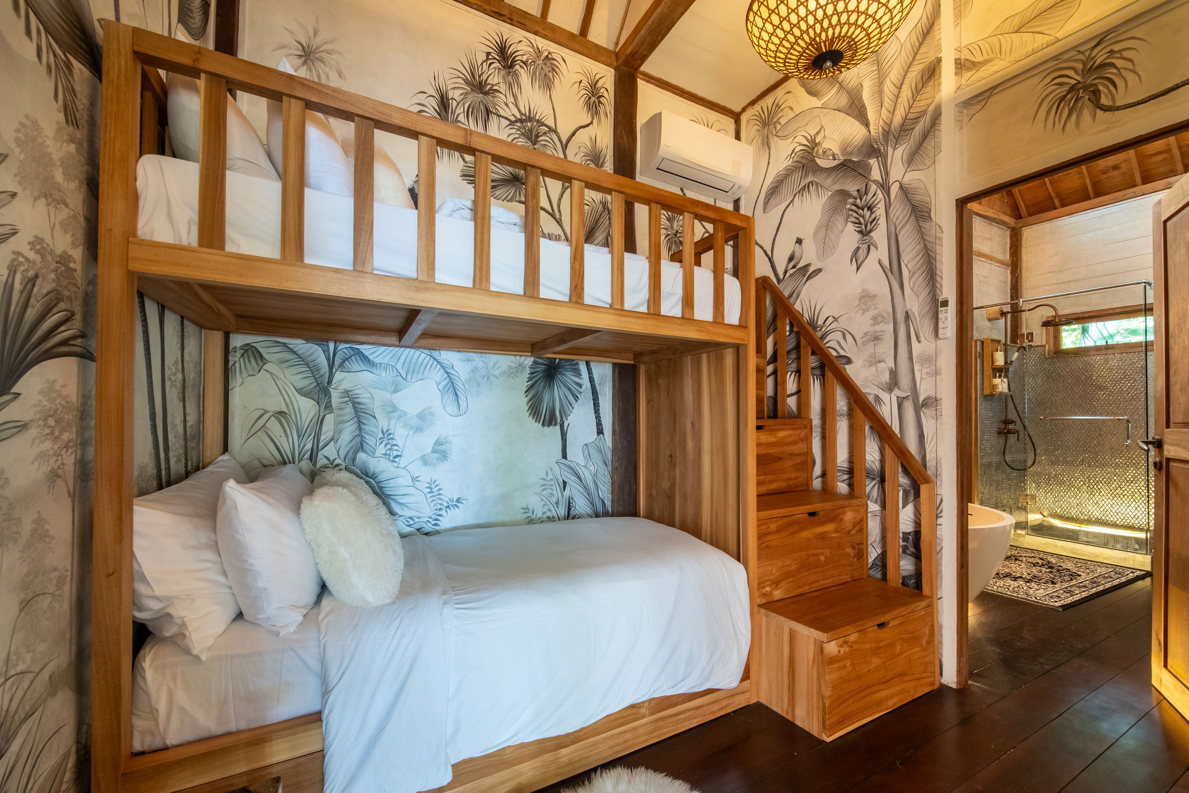 A built-in bunk bed against a painted botanical wall, stairs climbing to the upper berth.