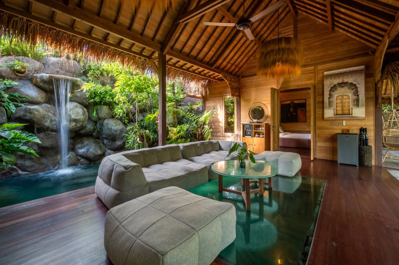 A full sectional sofa arrangement in Villa Eywa's living pavilion beside a rock waterfall.