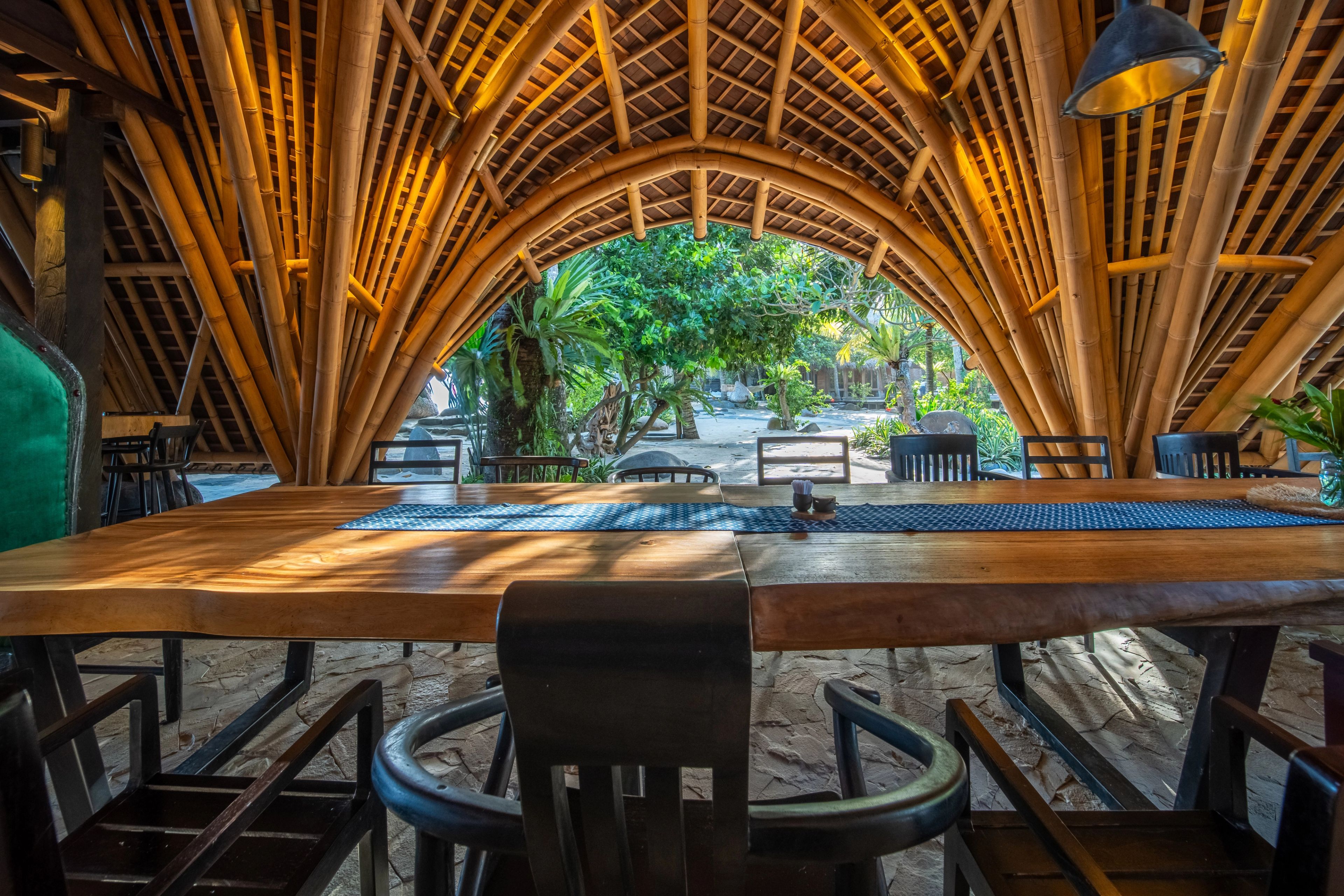 The bamboo ribs of the roof arching over the dining tables, the garden framed in the opening.