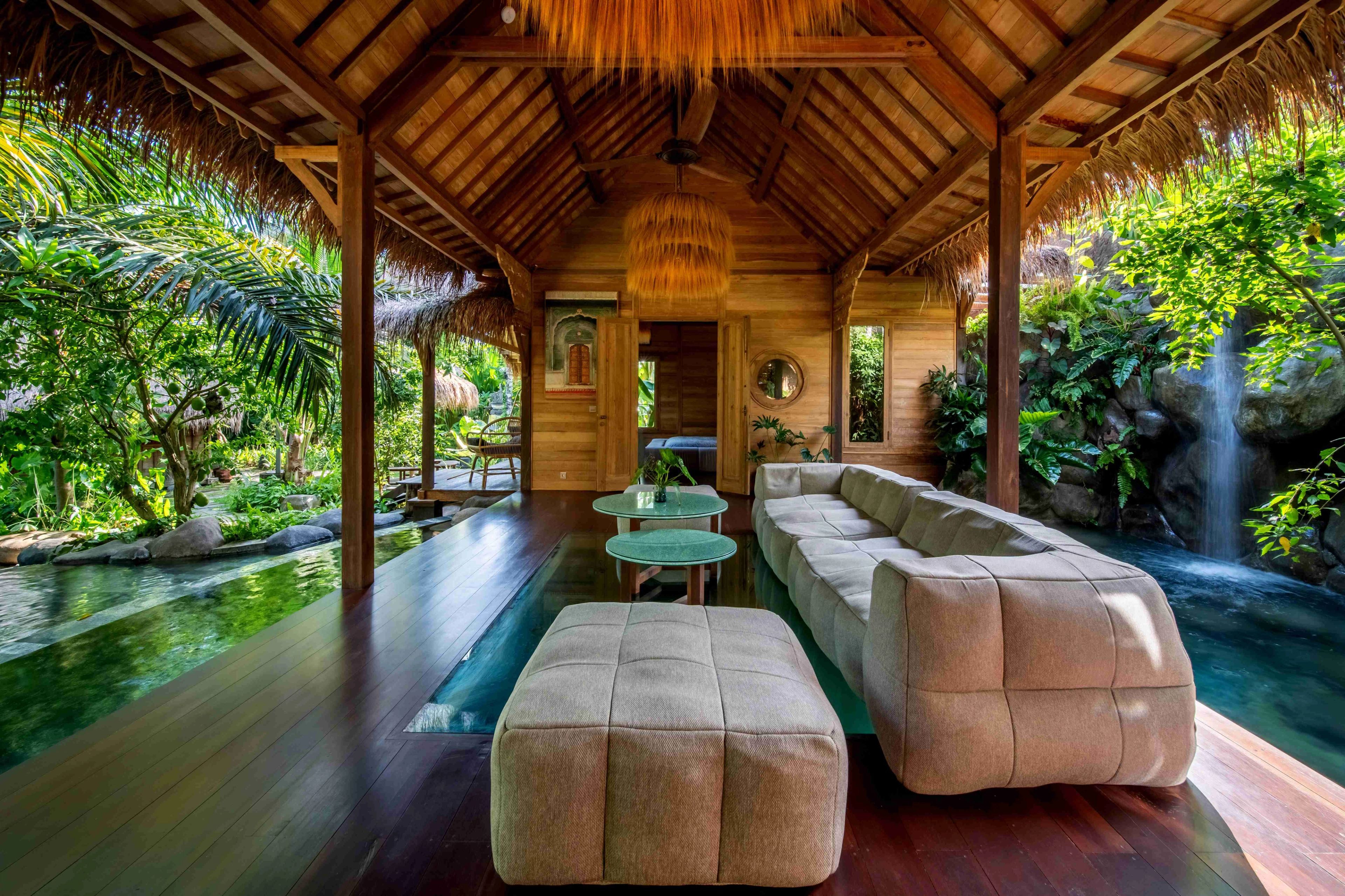 A sofa and ottoman on the timber floor of the open living room, the pool running along both sides.