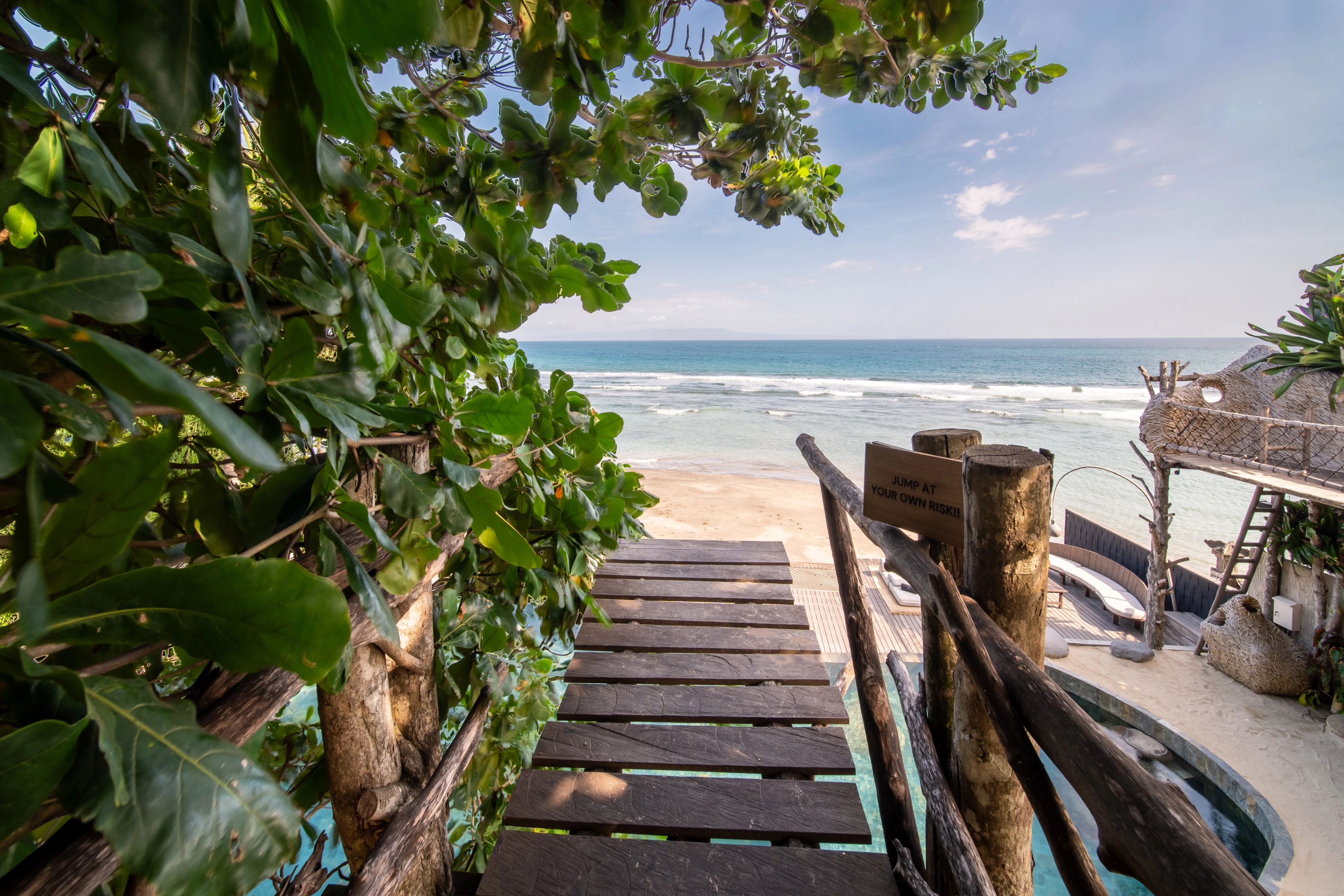 Timber steps running down to the sand past the boardwalk, the coastline visible beyond.