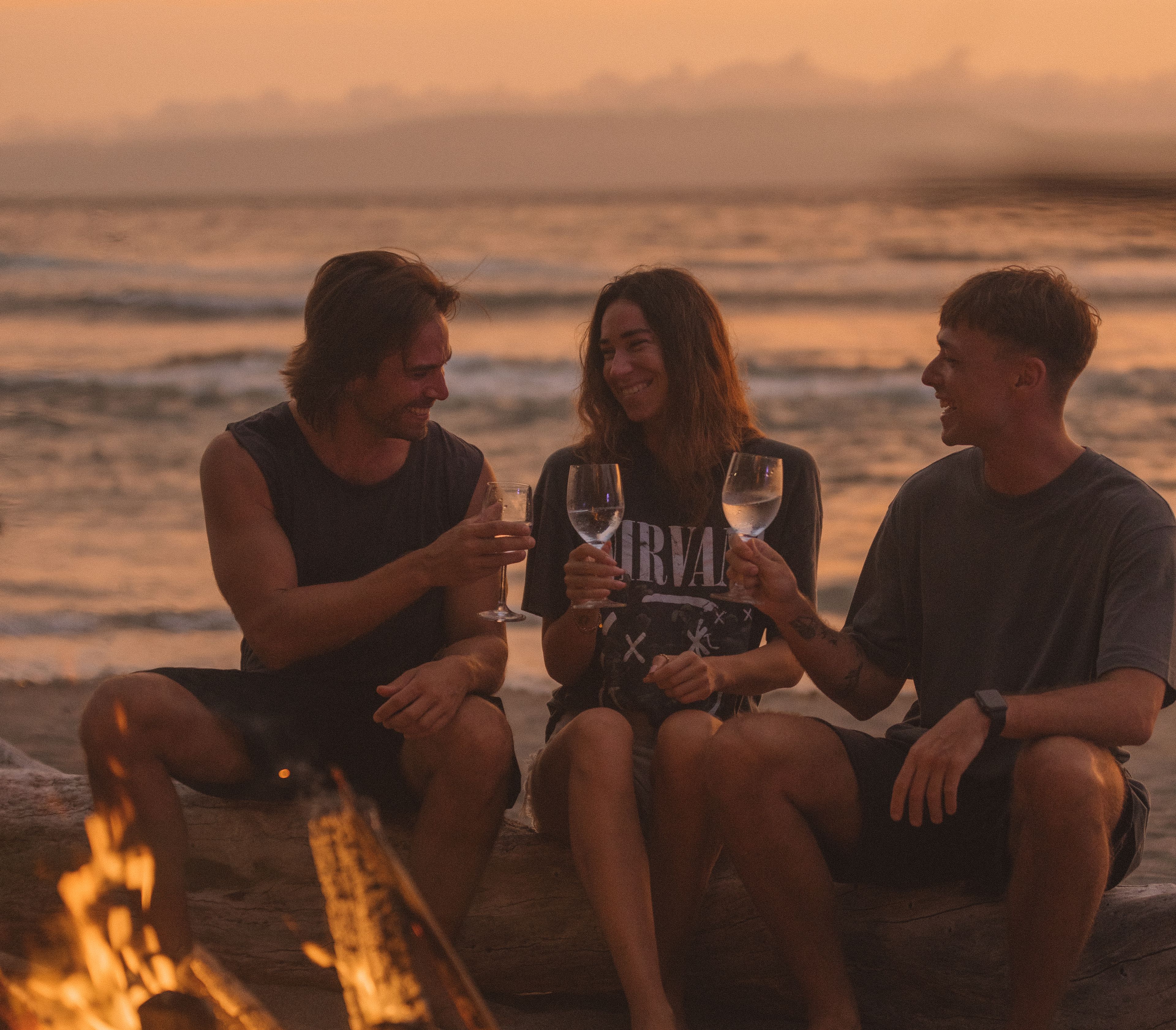 Group around a bonfire on the beach at night.