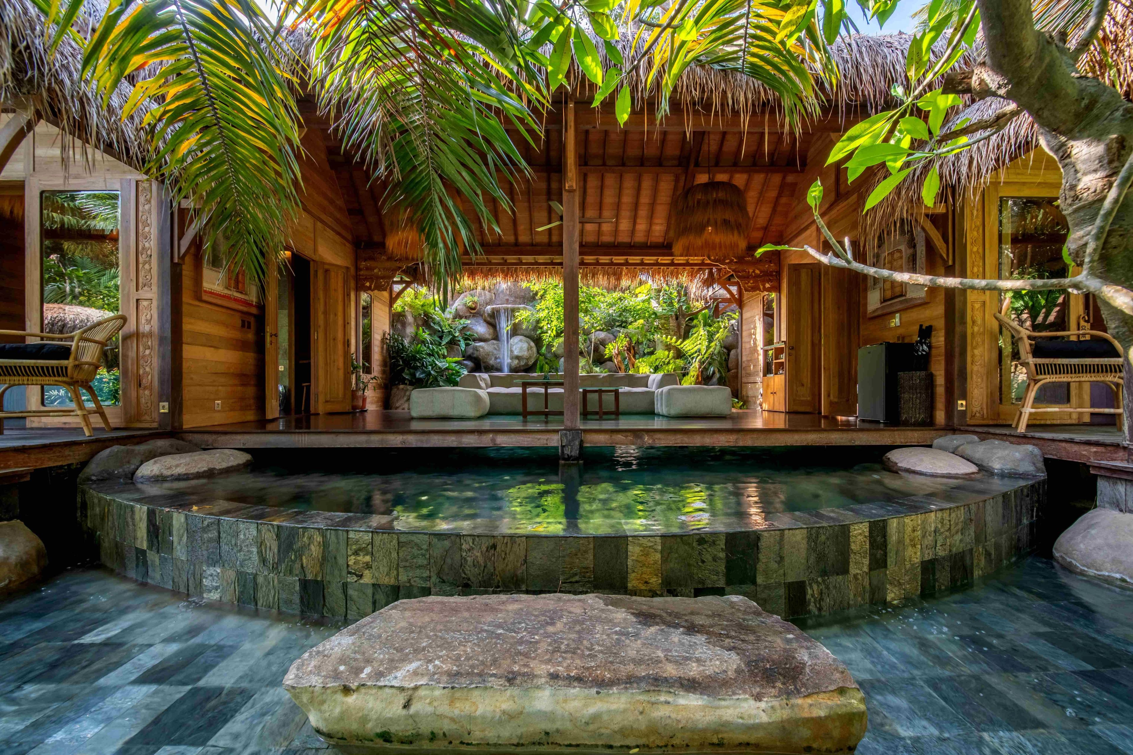 A stone-lined plunge pool set into the floor of the villa, a slab step at its edge.
