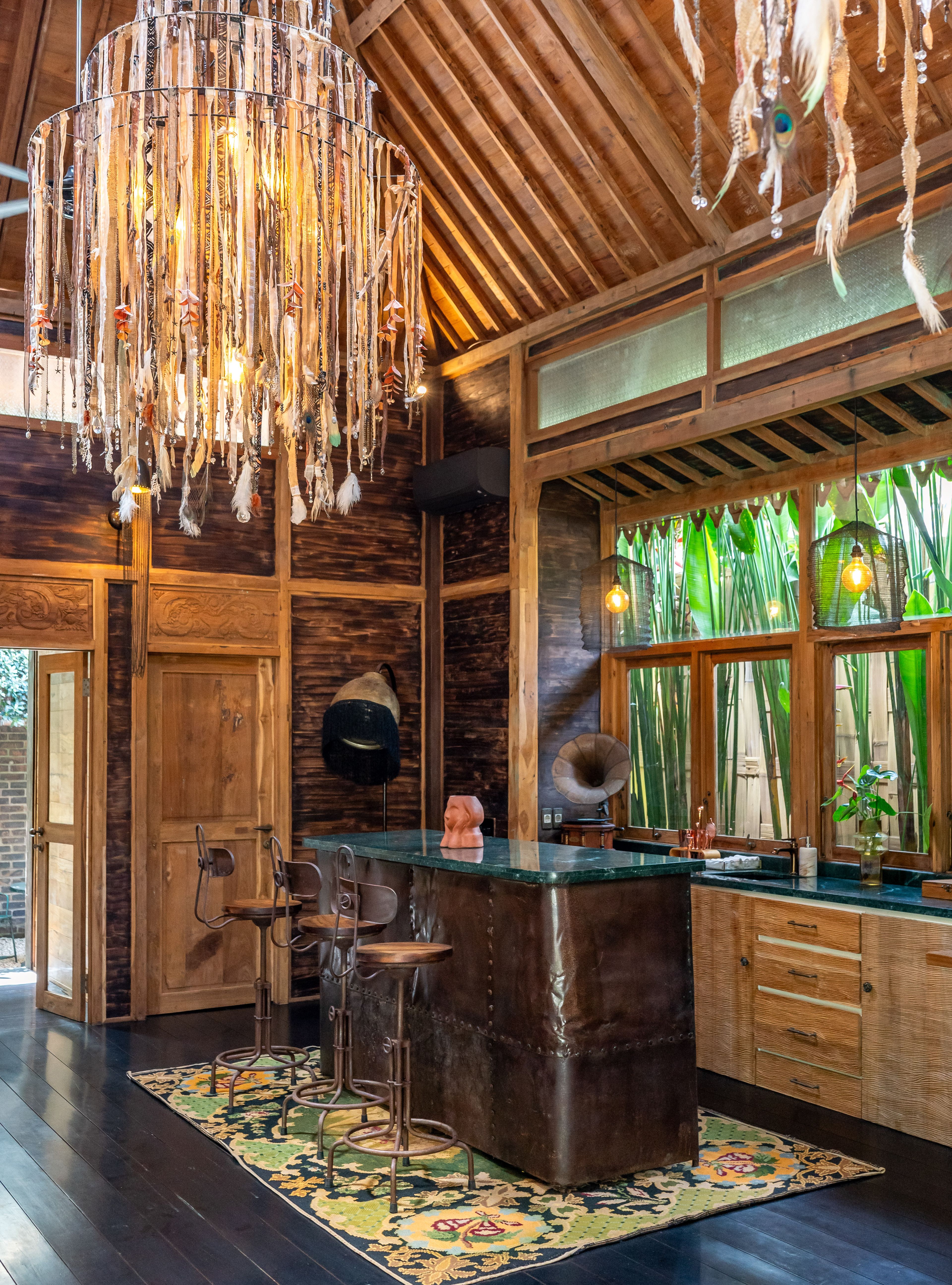 Stools at the green stone bar, a gramophone and a hat on the counter, bamboo outside the windows.