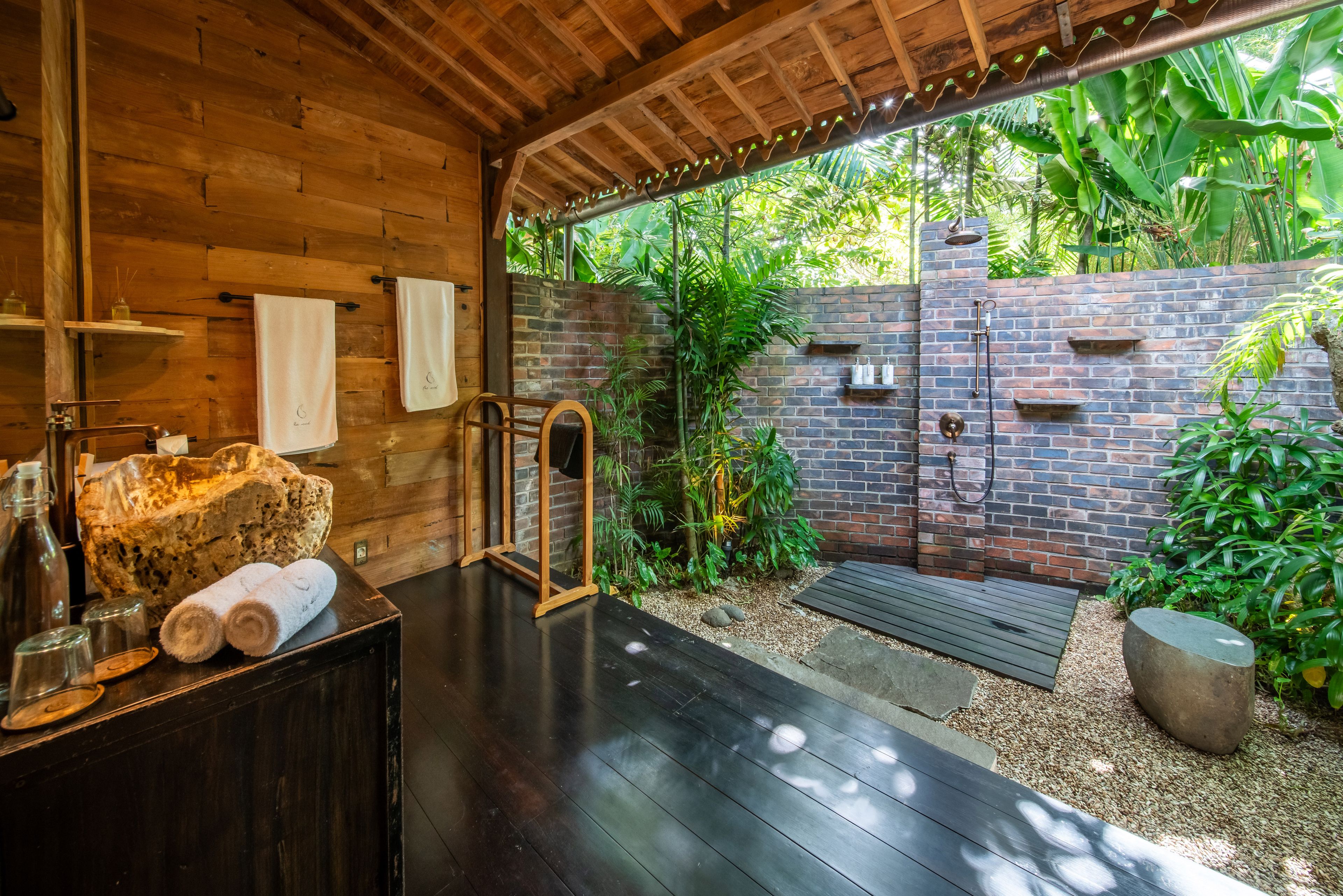 The bathroom opening onto a brick-walled outdoor shower, towels folded on the counter.