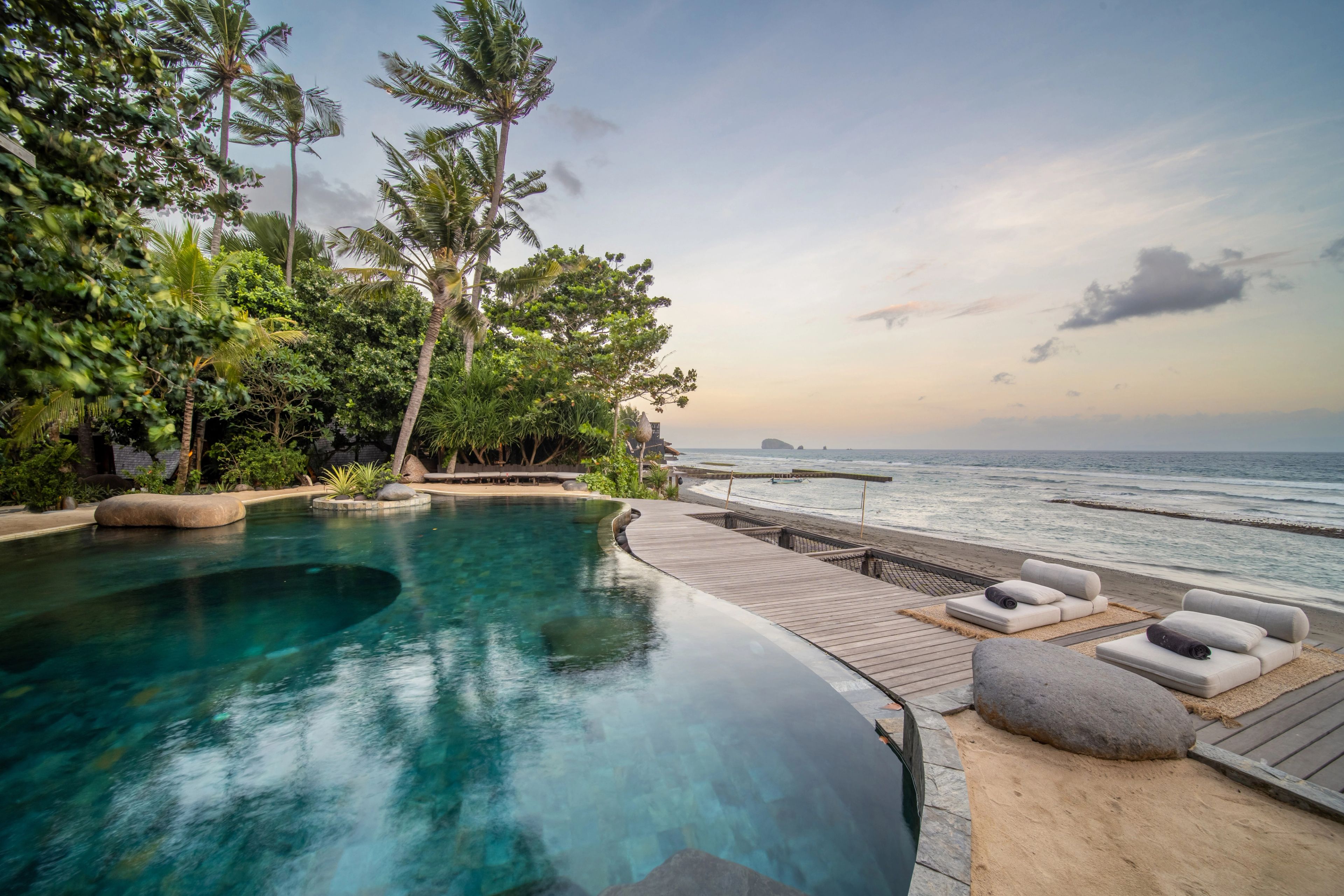 The infinity pool at dawn, the deck and loungers running along its seaward edge.