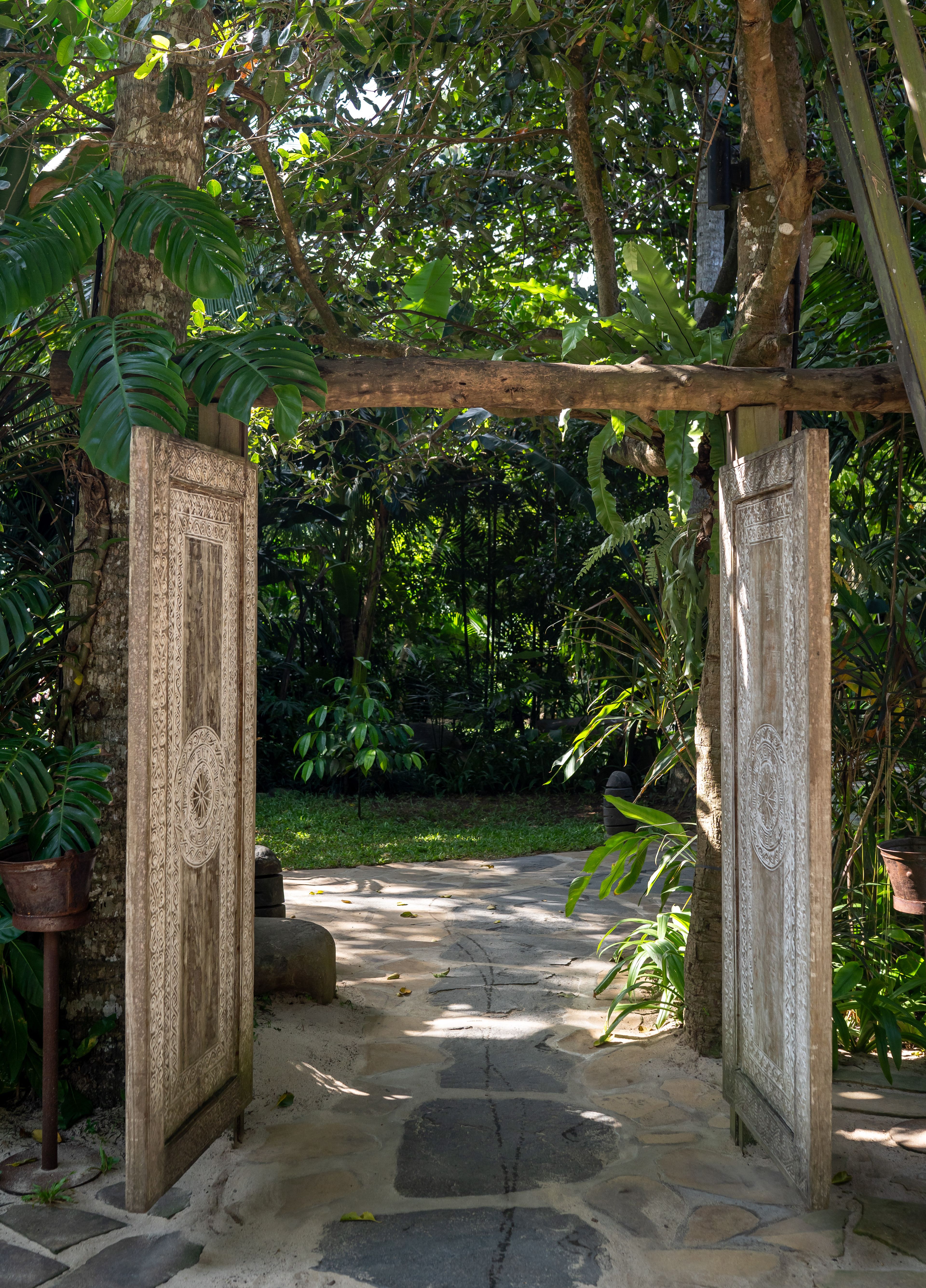 The carved wooden entrance gate to the estate, framed by jungle.