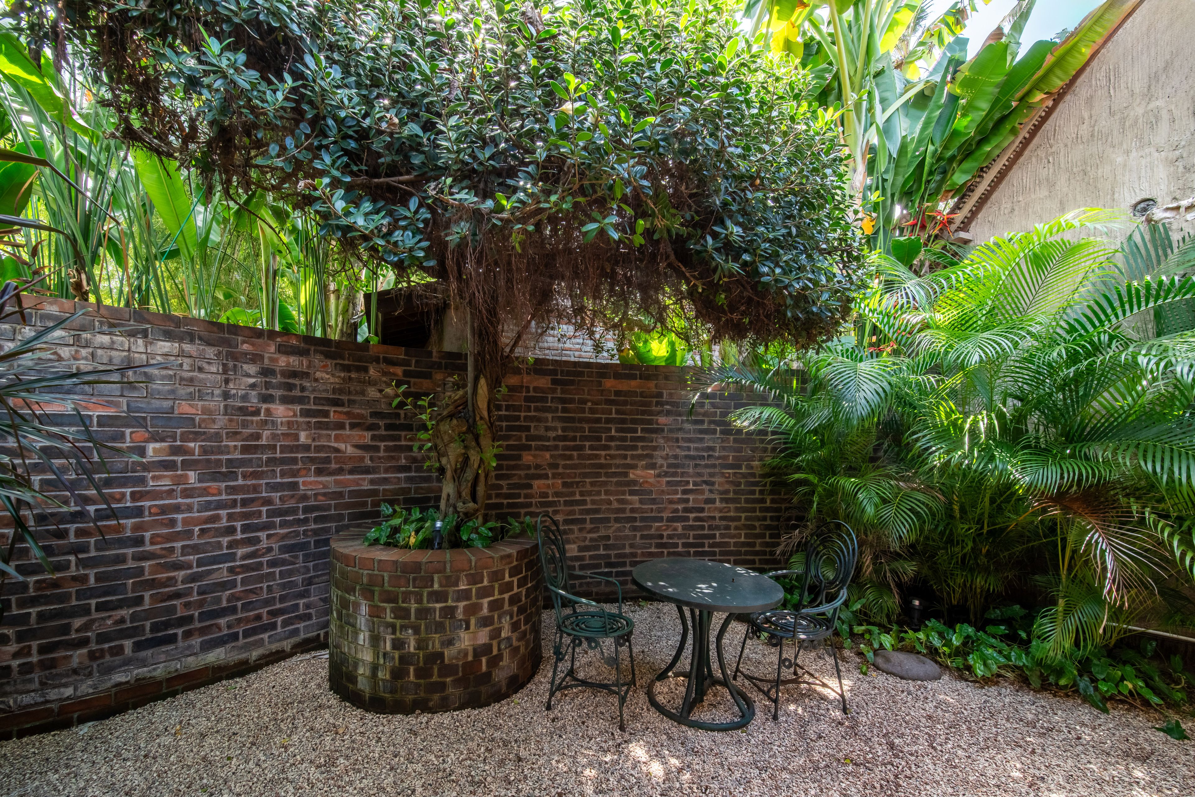 A bistro table set on gravel in the brick-walled courtyard, planting along the walls.