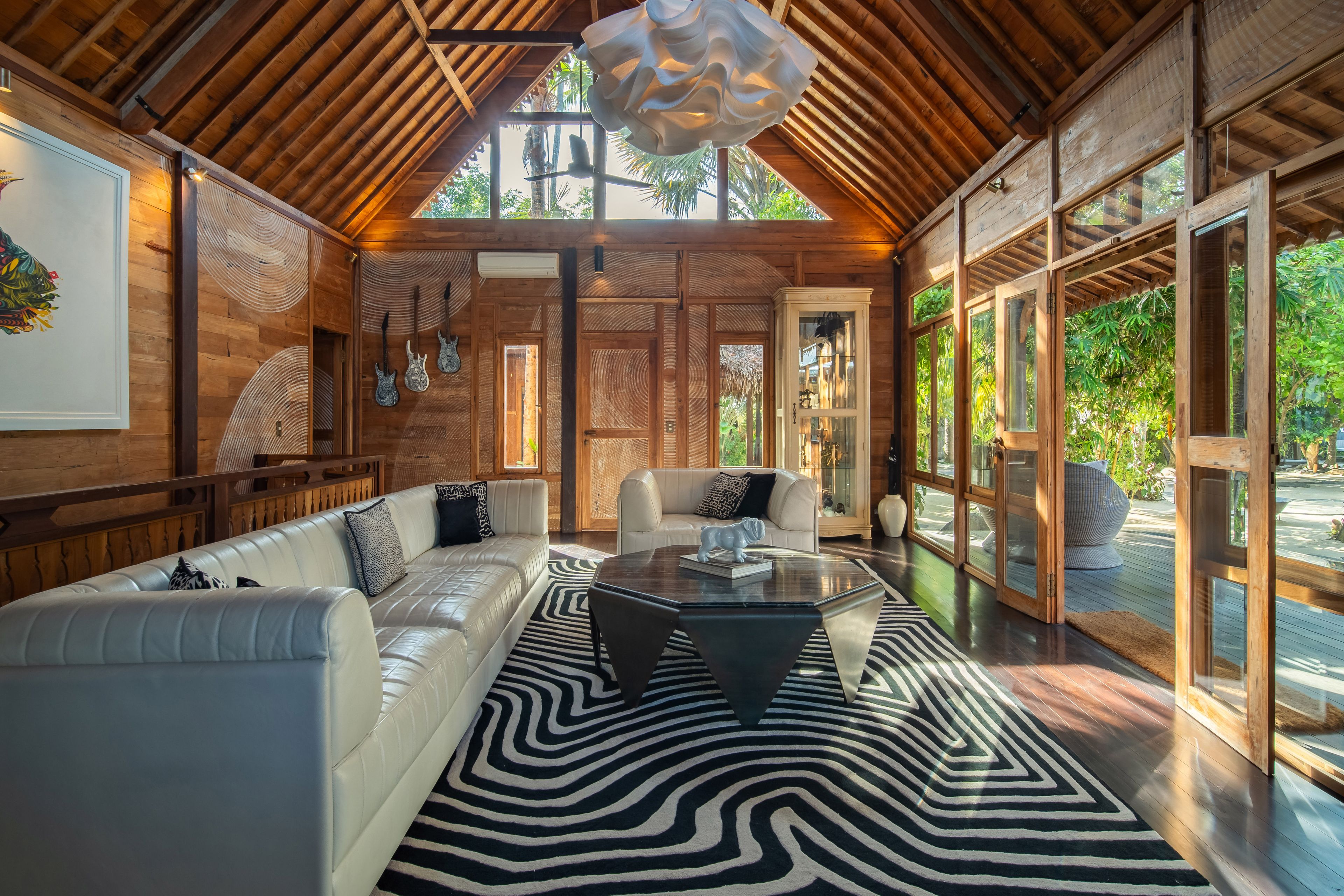 White sectional sofas around a low table on a black-and-white striped rug, doors open to the terrace.