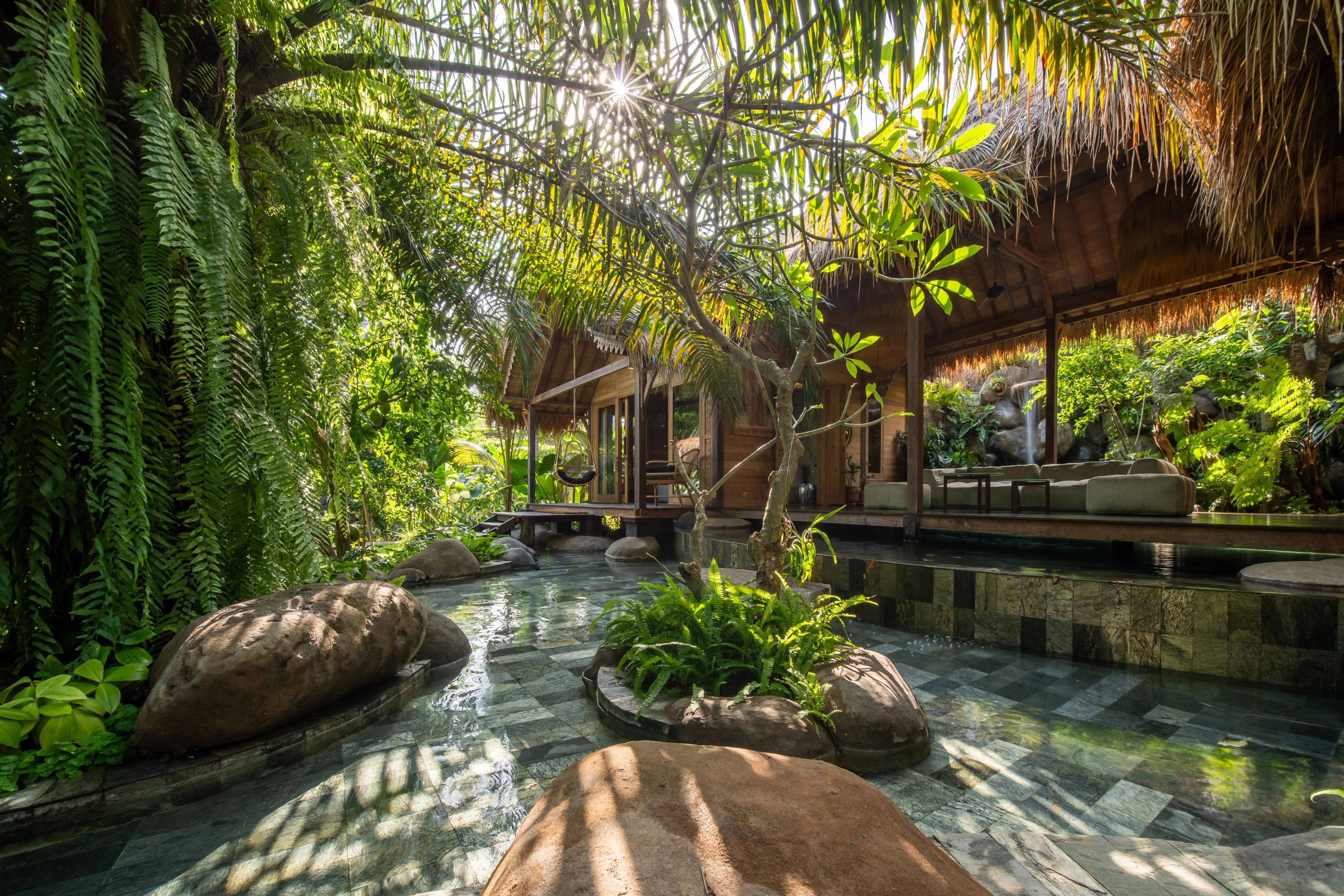 Villa Eywa's jungle-shrouded pavilion with pool, waterfall, and sunlight streaming through palm fronds.