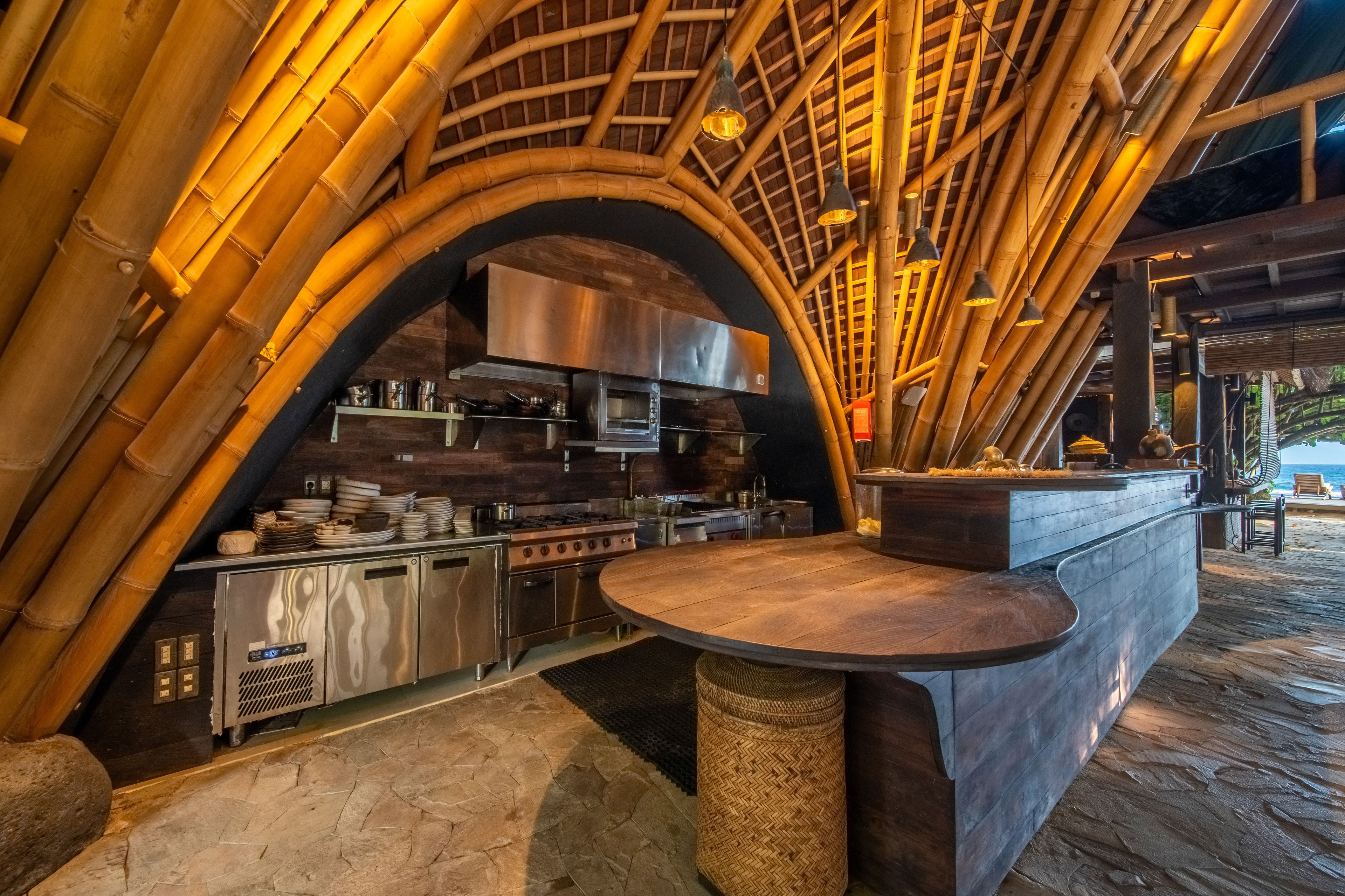 The stainless open kitchen and pass set beneath the bamboo arch of the restaurant.