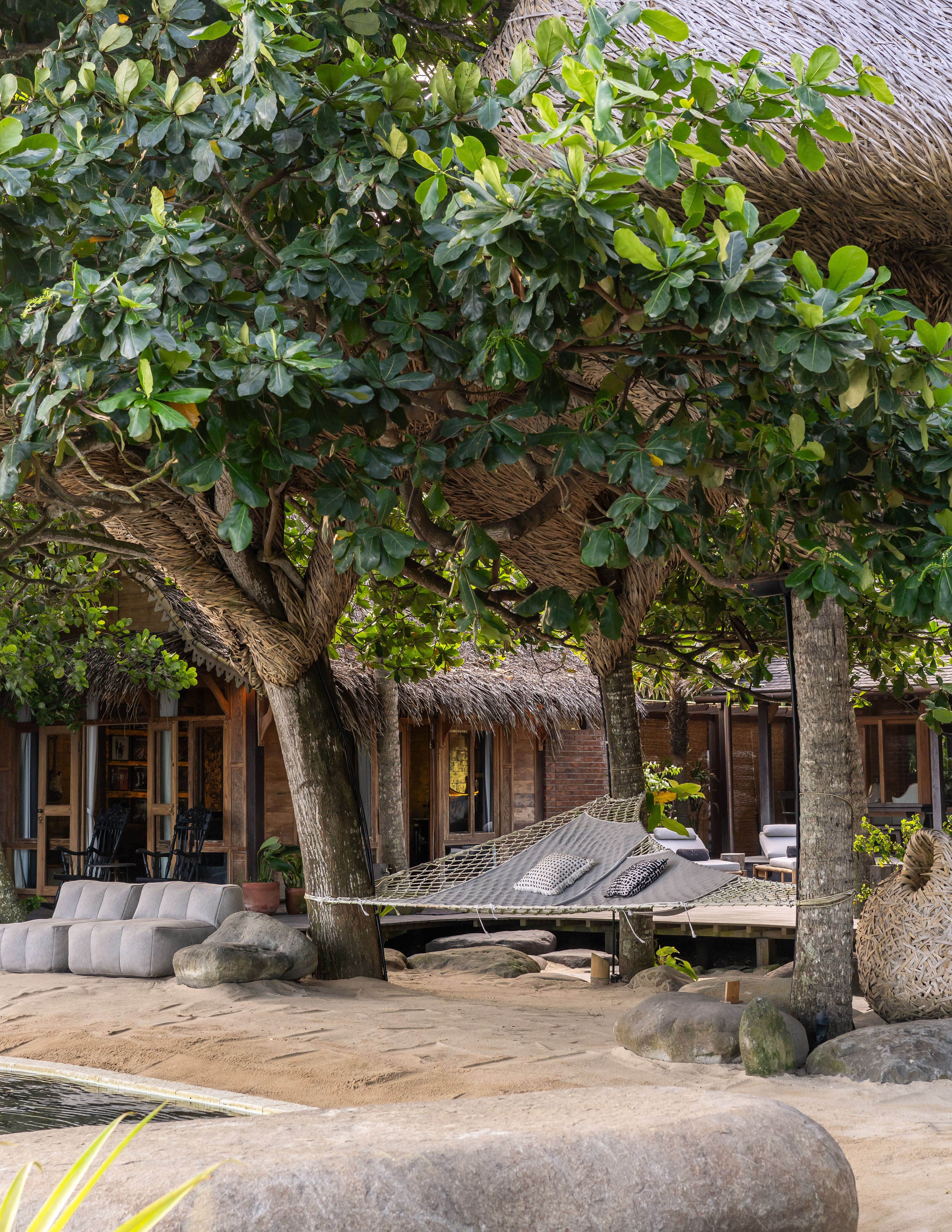 A hammock slung under the trees in the courtyard, the villa's veranda behind.