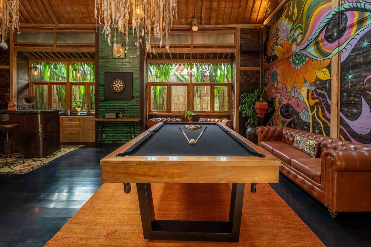 Wide-angle view of the games room featuring a pool table and mural wall.