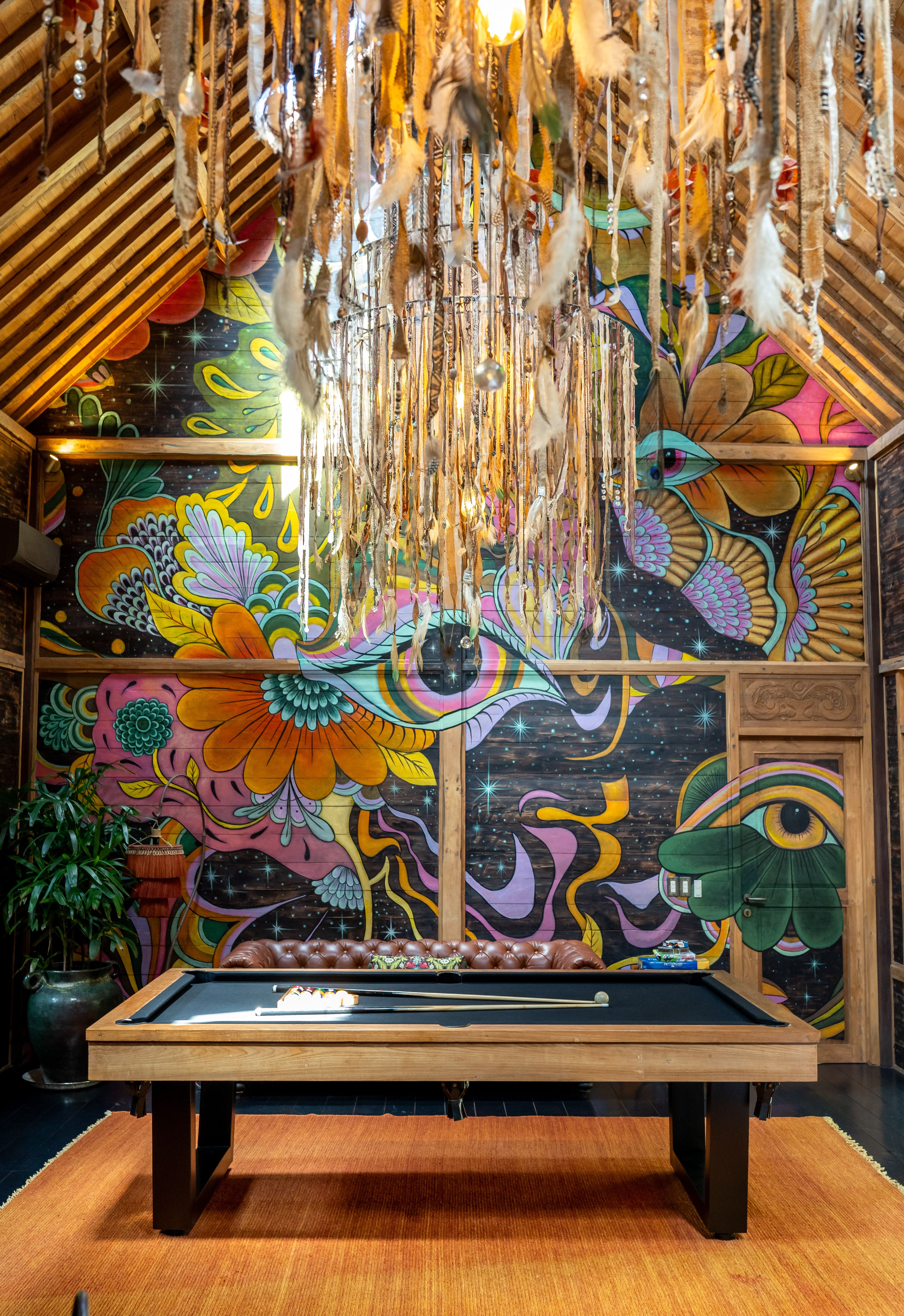 The full painted mural of flowers, birds and eyes filling the wall of the games room.