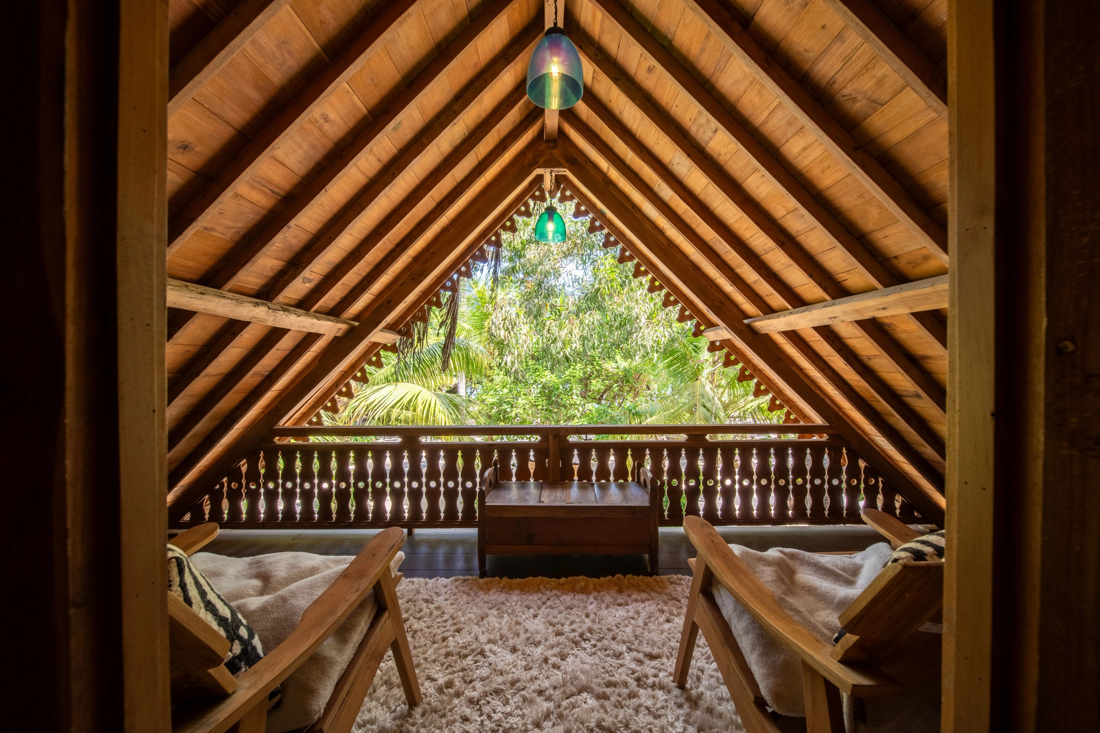 The pitched timber gable framing a daybed and safari chairs, garden beyond the balustrade.