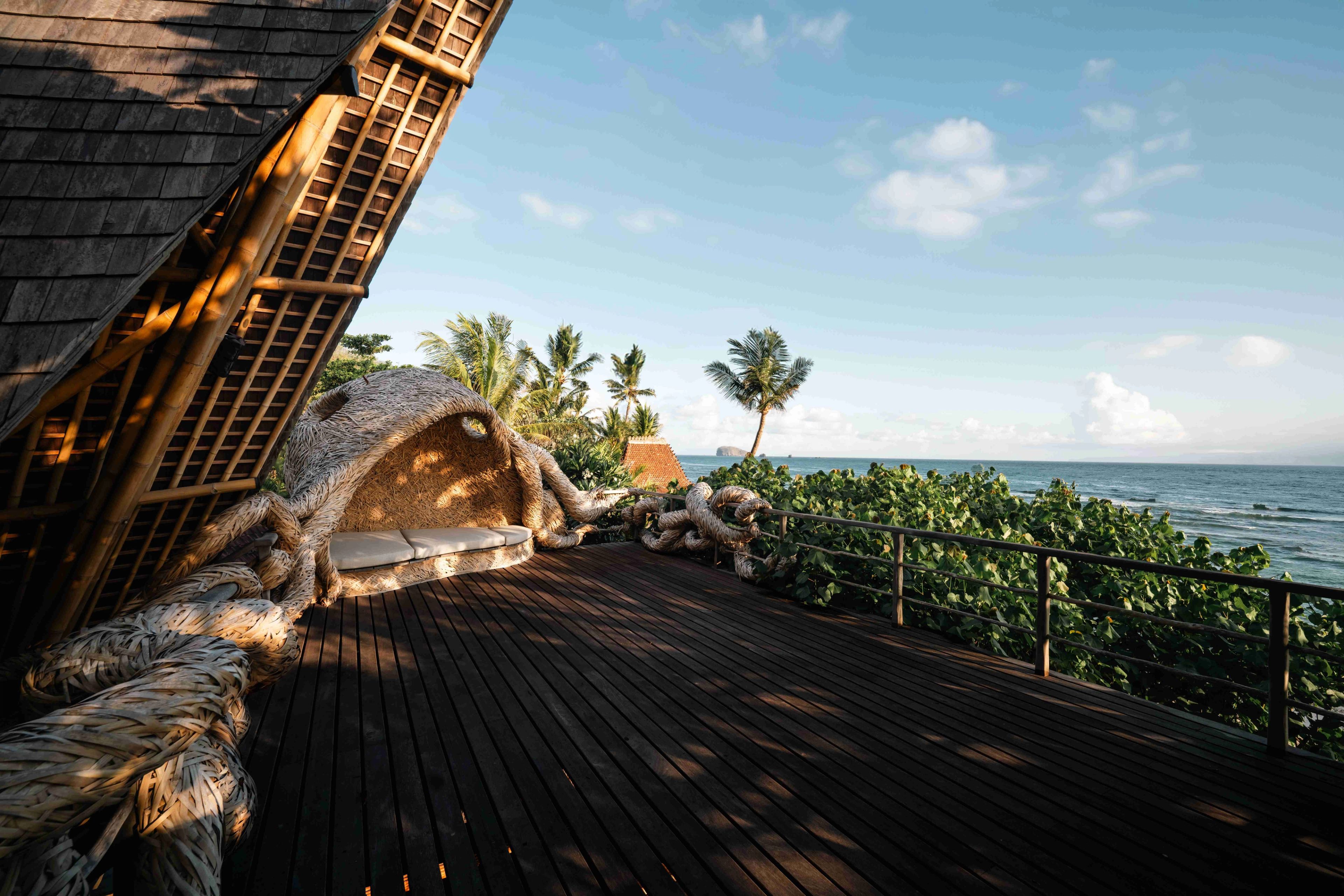Low sun across the boards of the shala, palms and the ocean framed by the canopy posts.