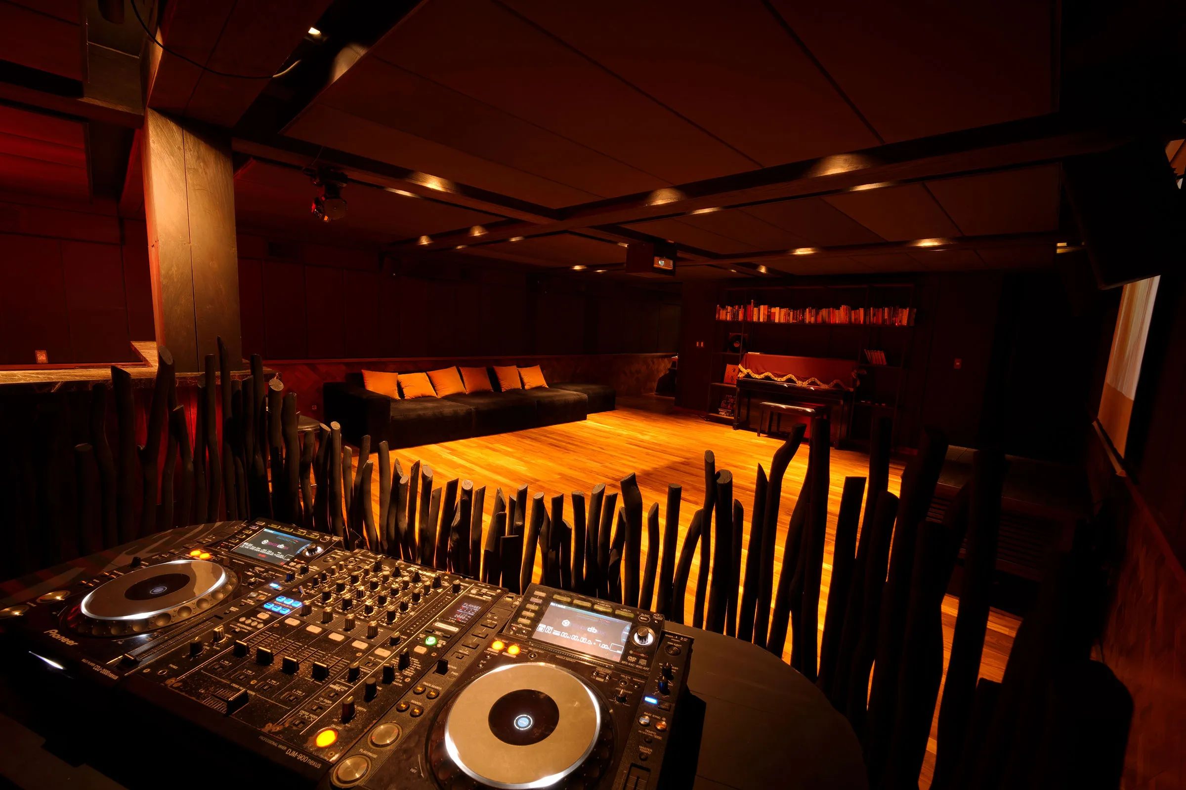 A CDJ setup on the booth in the basement club, the lit dance floor beyond.