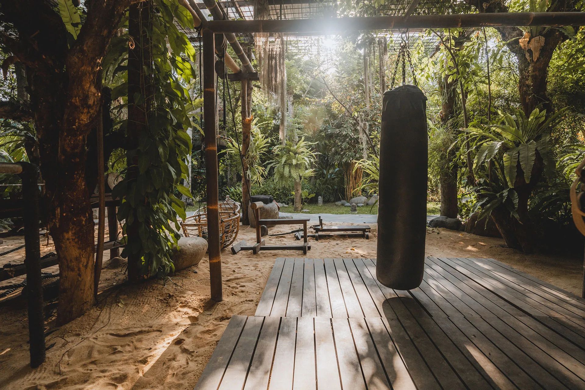 The timber training deck running through the gym, a heavy bag at its far end among the trees.