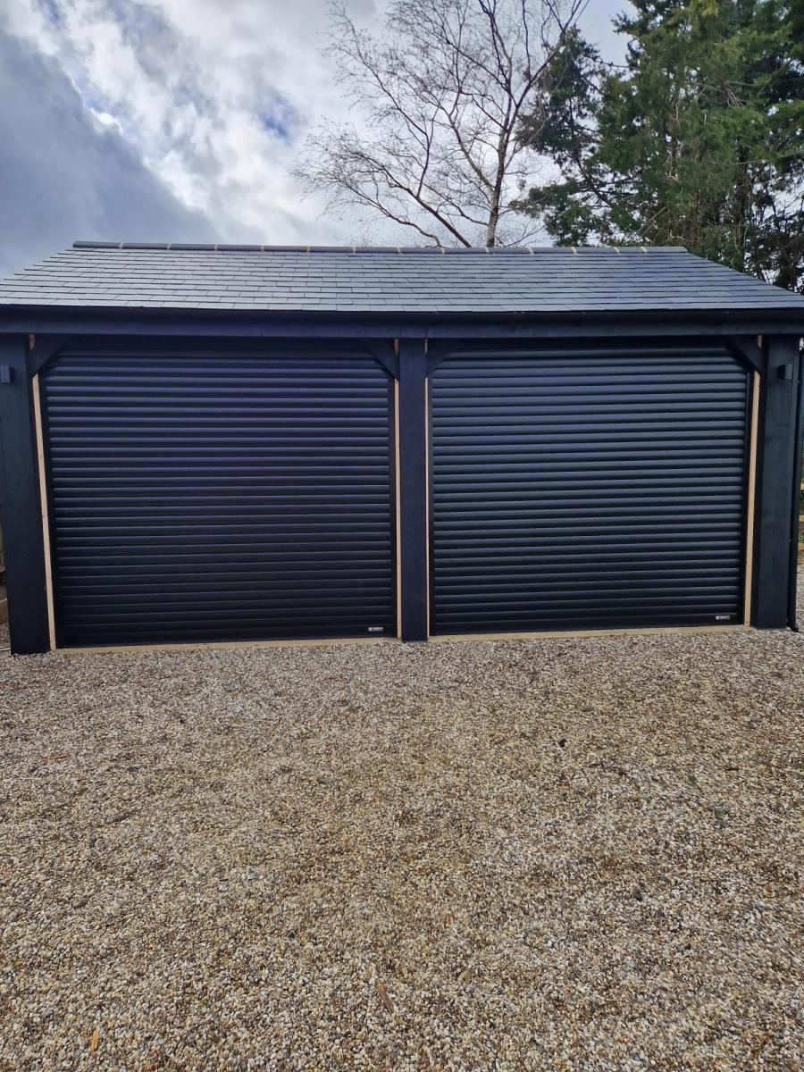 Black roller garage doors in an oak-framed garage
