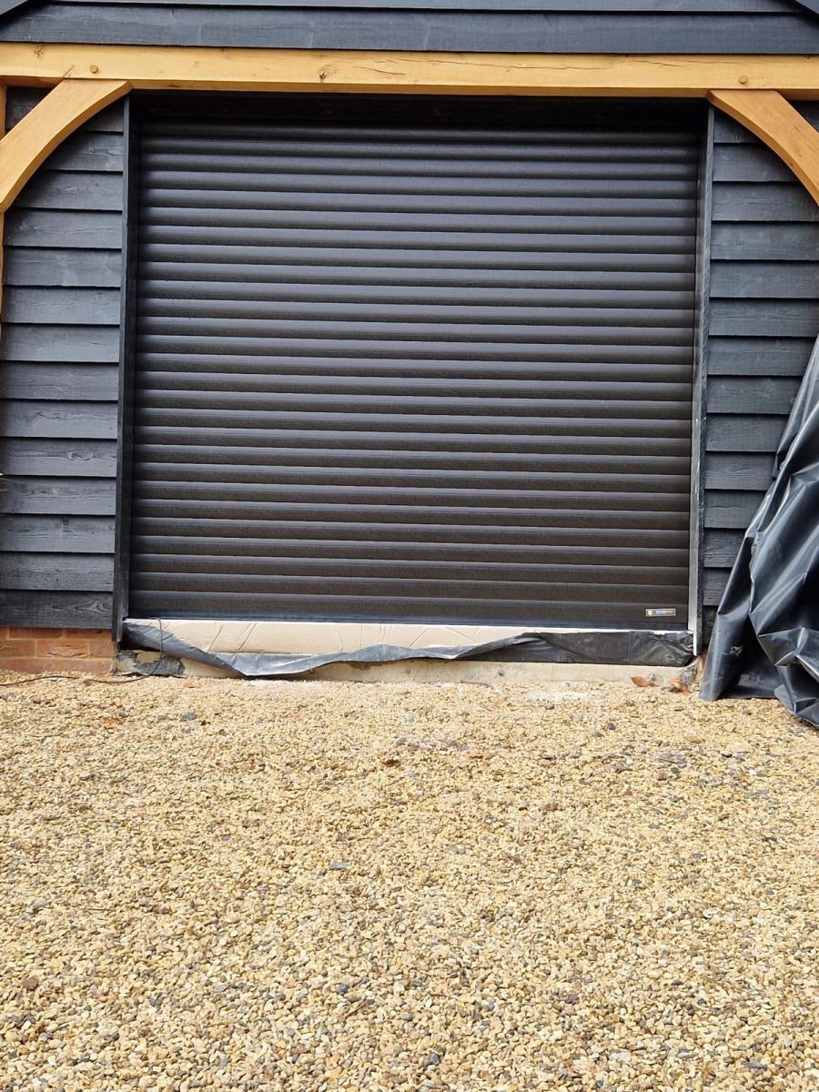 Black roller garage door in an oak-framed garage