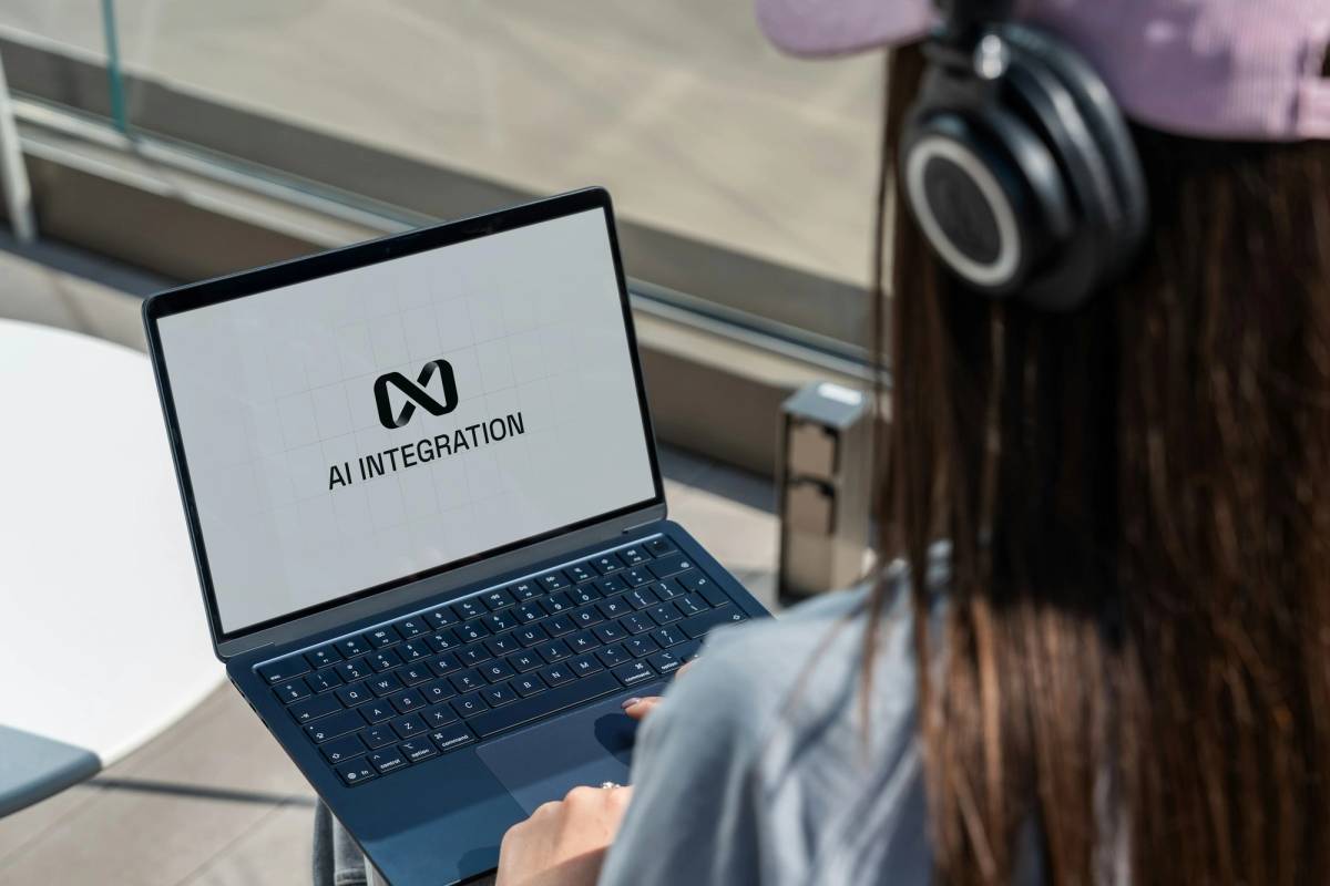 Person using laptop with ai integration logo displayed.