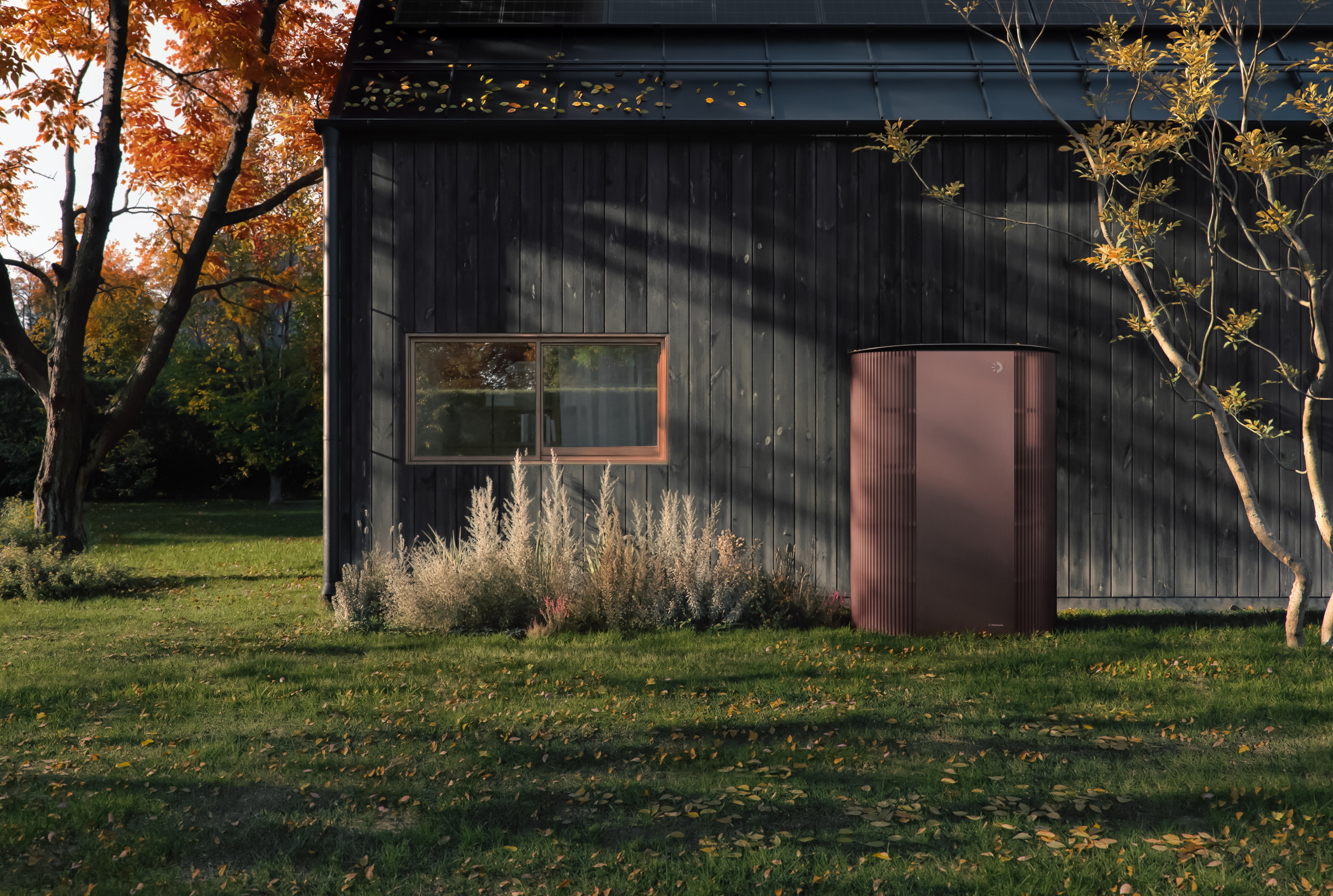 A modern Danish-style house with a dark wooden exterior, a pitched roof, and a red Photoncycle unit outside, surrounded by autumn trees and sunlight.