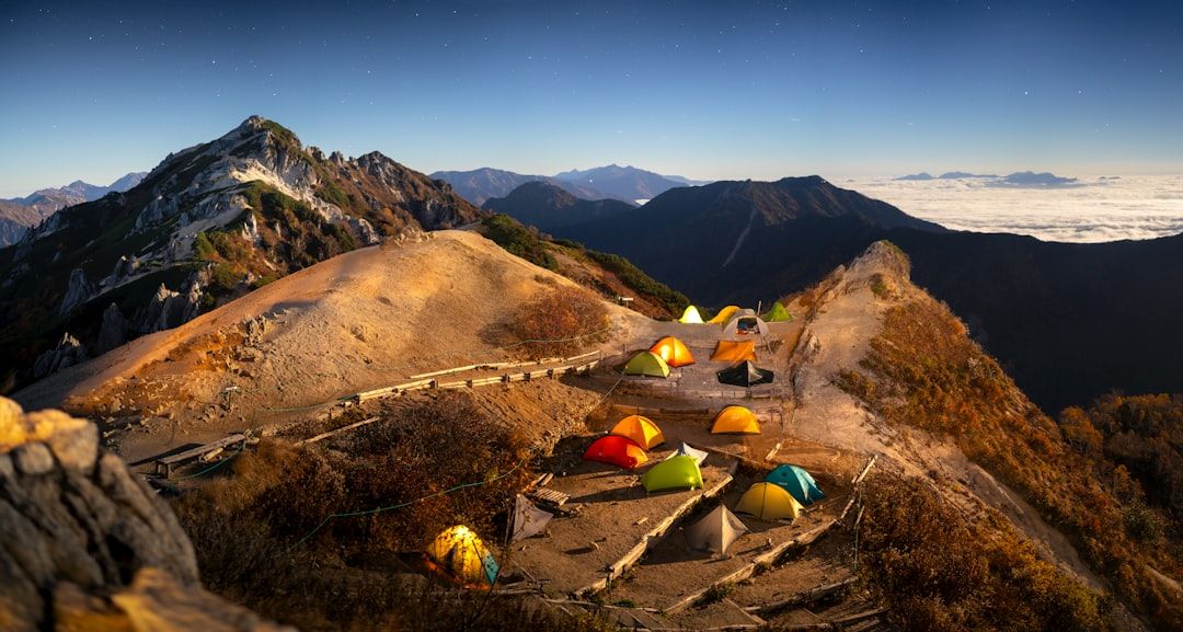 Tente de bivouac installée sur un sommet de montagne sous un ciel étoilé