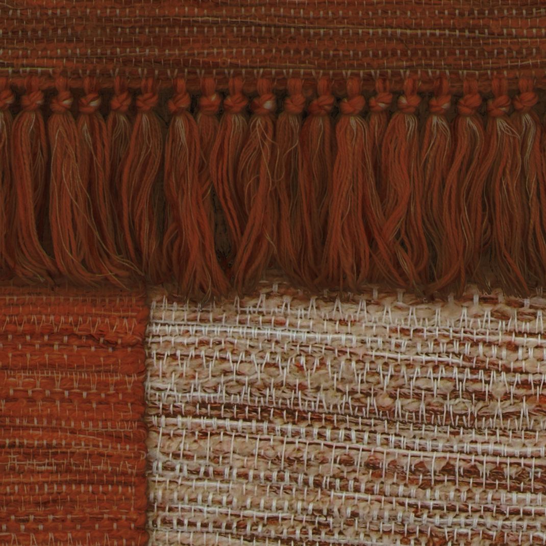 Terracotta behang met verschillende geweven kleden.