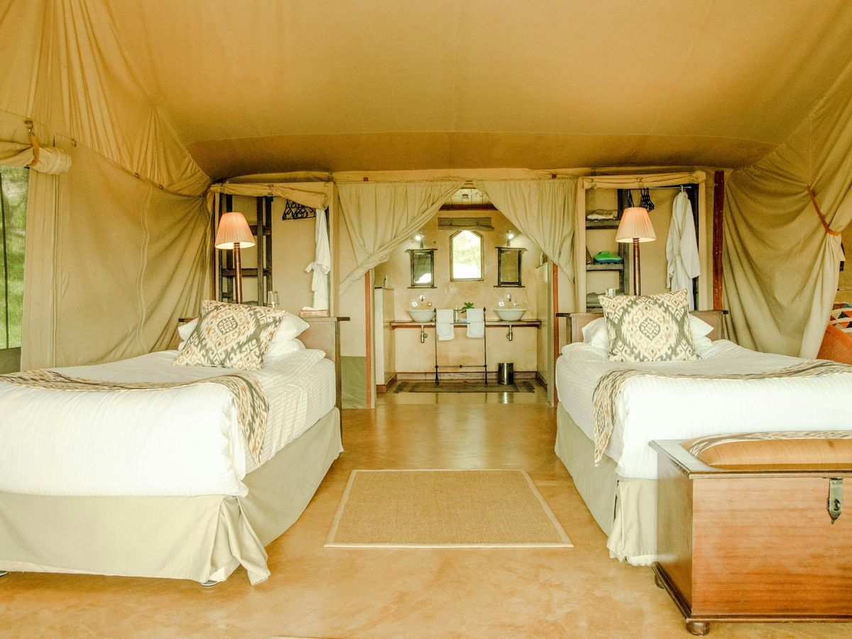 Twin beds and lantern light inside a luxury safari tent