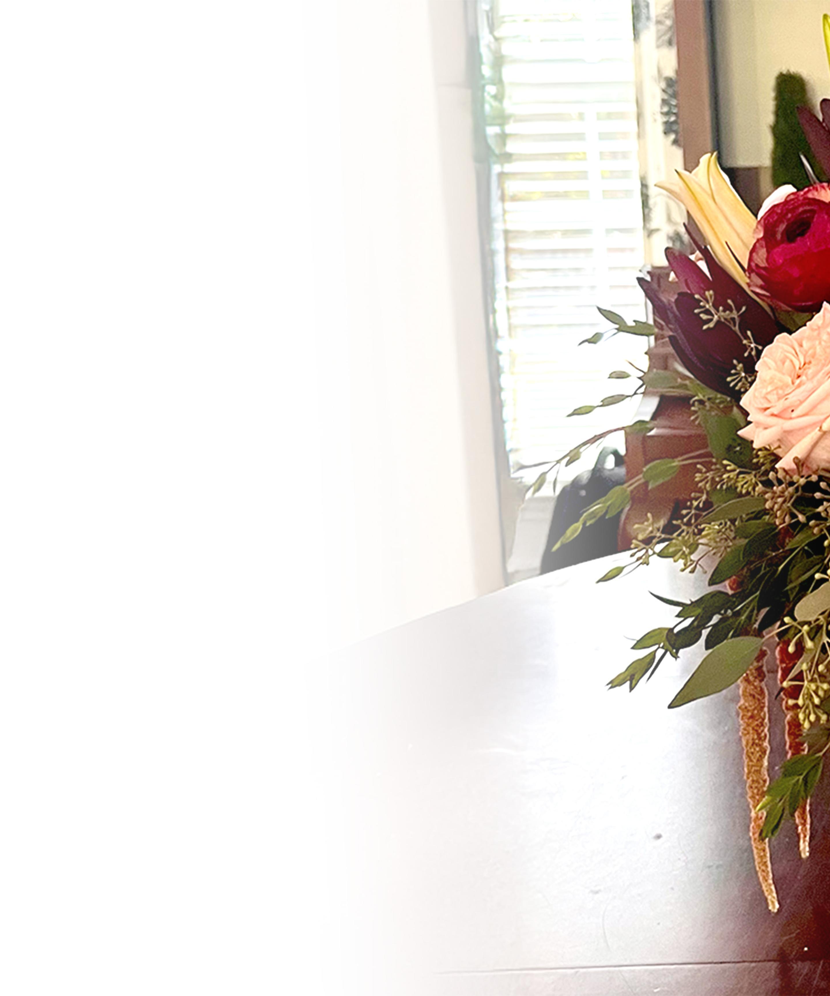 a bouquet of flowers is sitting on a table in front of a window .