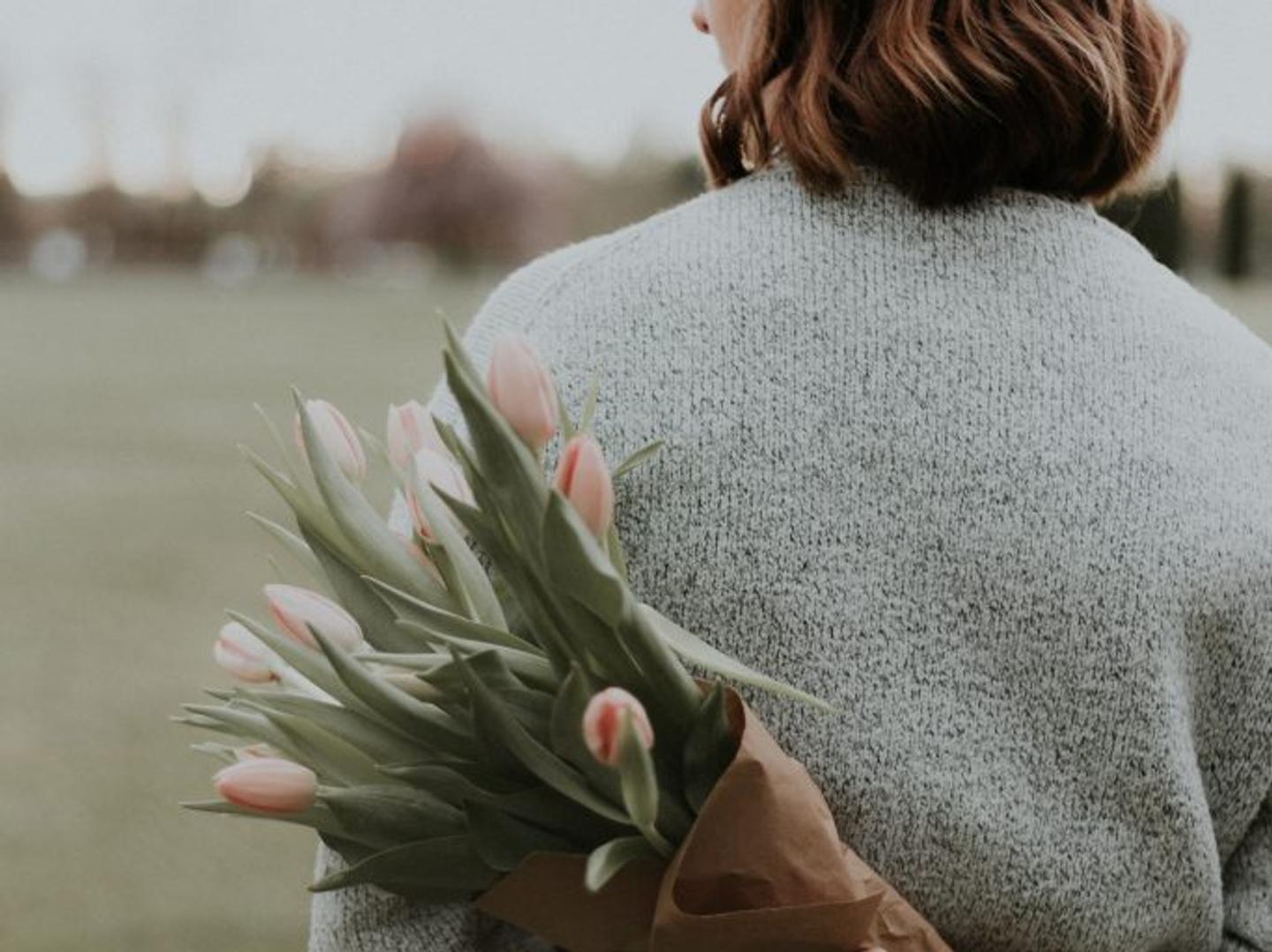 a woman is holding a bouquet of flowers behind her back .
