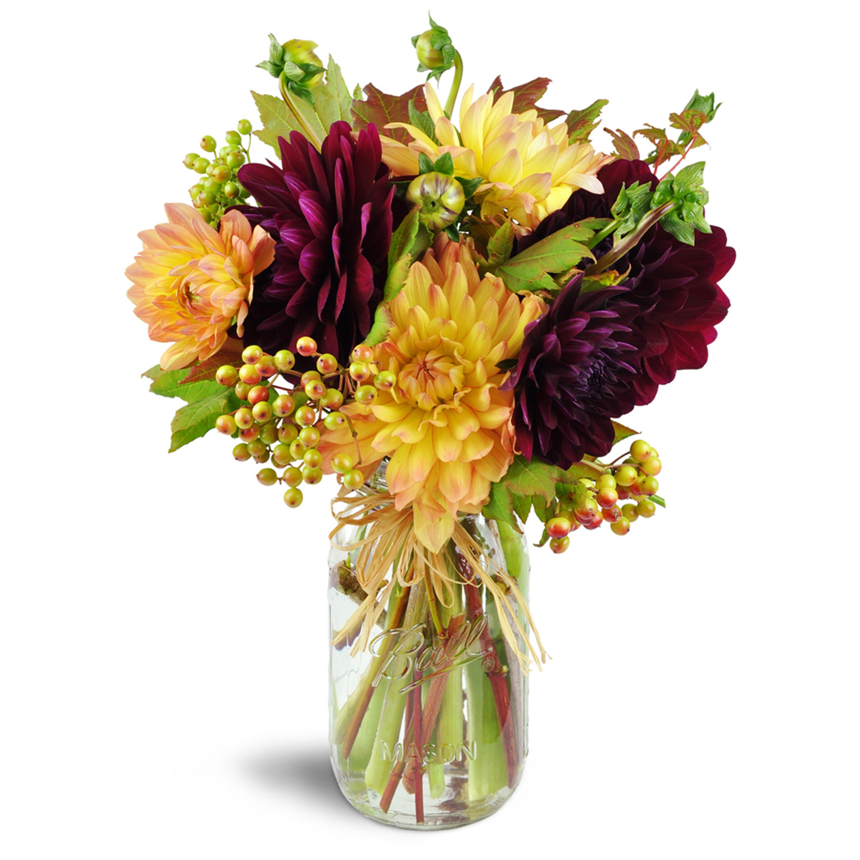 A beautiful unique arrangement in a mason jar with orange and deep red flowers