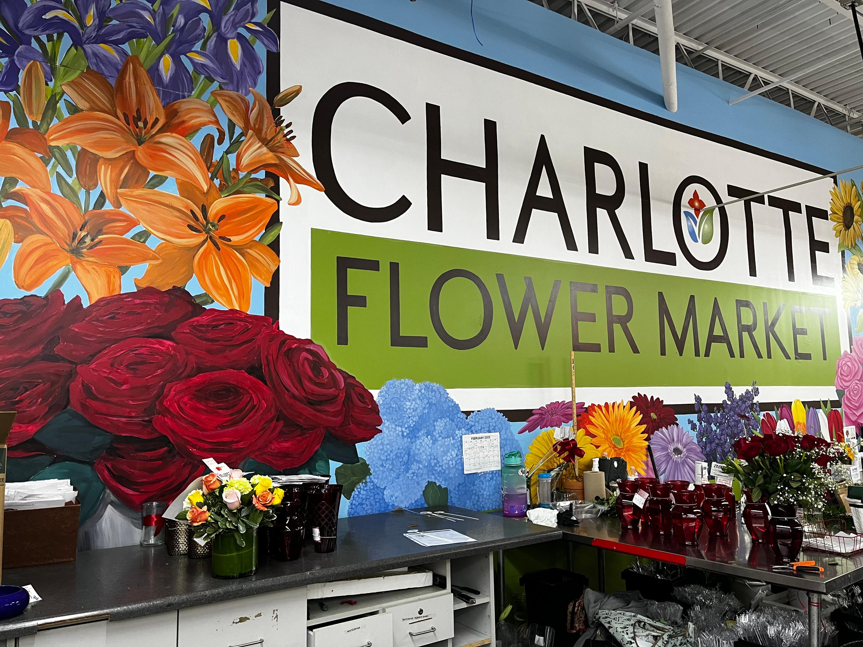 Mural painting of the Charlotte Flower Market. Painting inside the flower shop with big bold flowers.