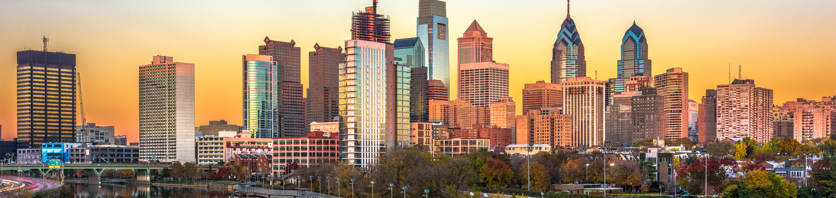 The Philadelphia skyline in closeup with a blurred background of towering skyscrapers reflecting the golden hues of sunset in Pennsylvania.