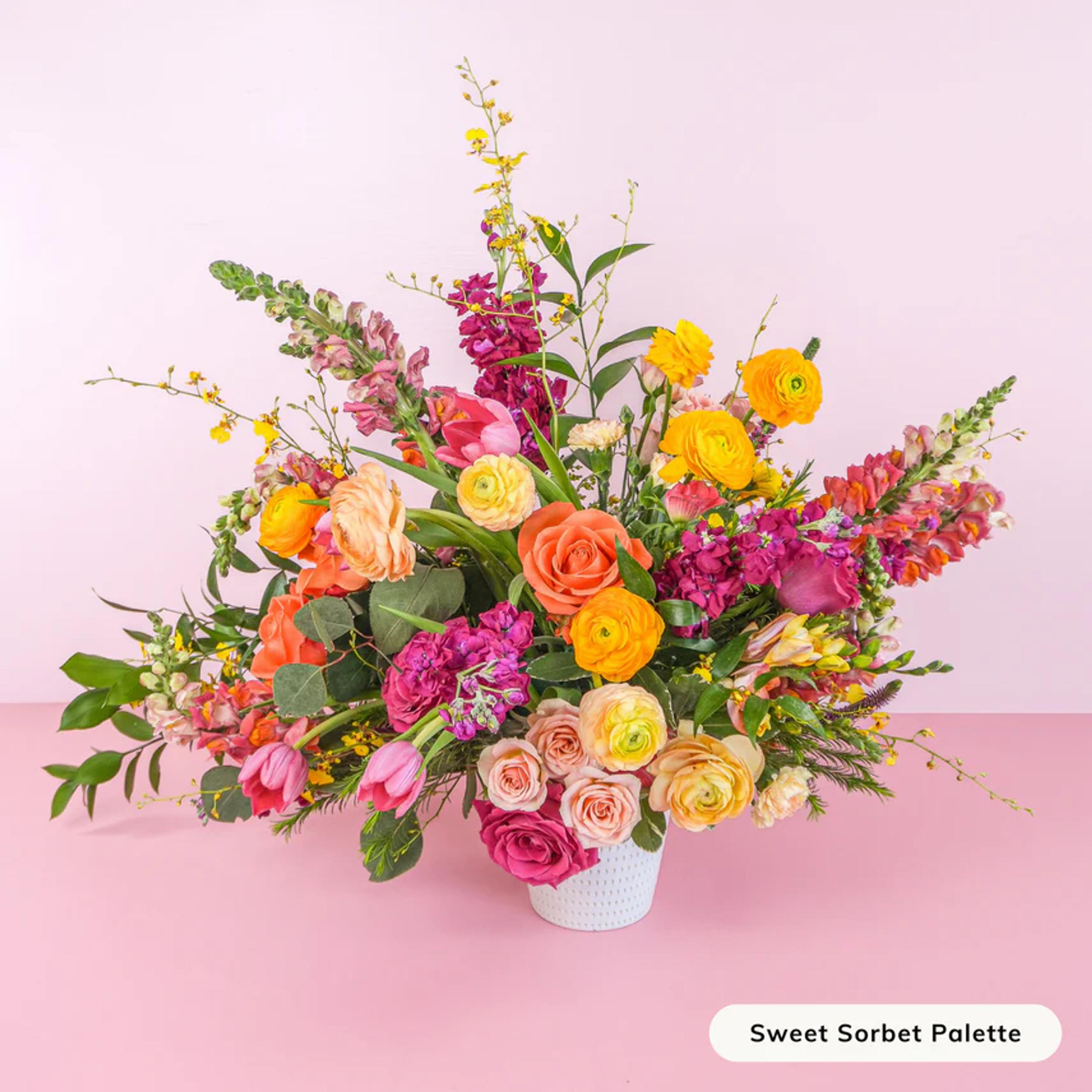 a vase filled with colorful flowers is sitting on a pink table .