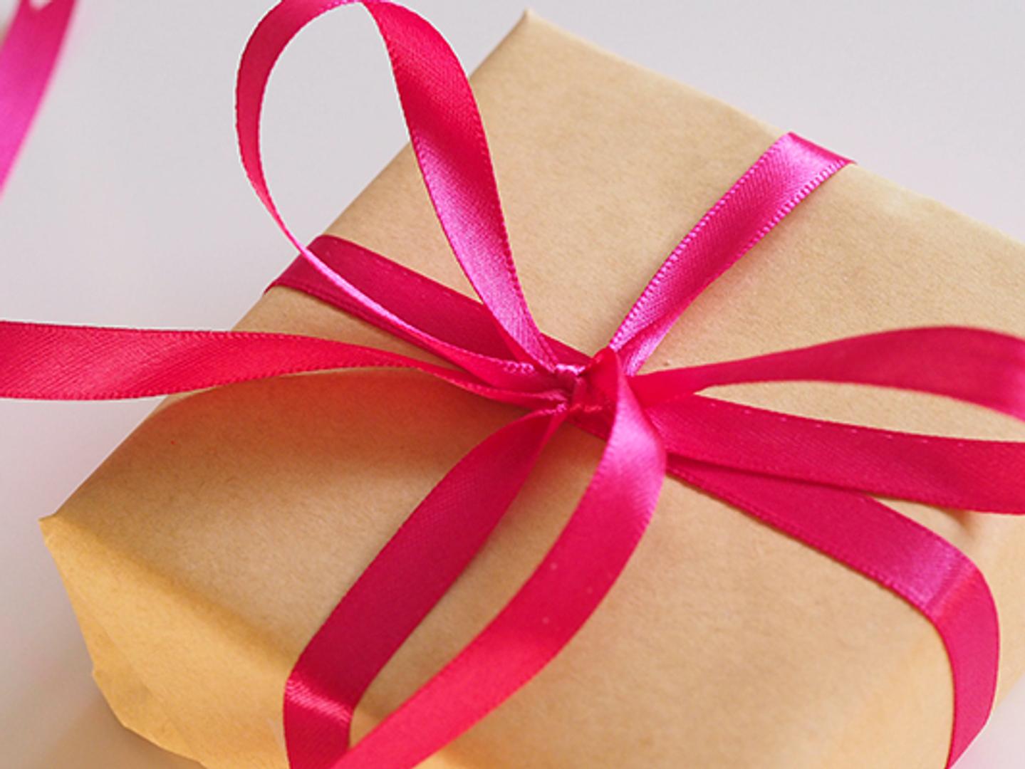 a gift wrapped in brown paper and tied with a pink ribbon .