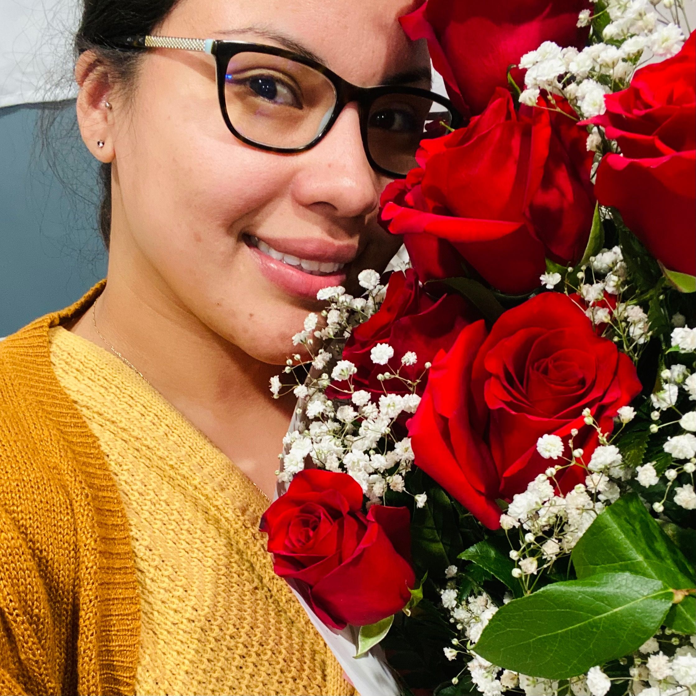 Contented woman with glasses posing with a vibrant bouquet of red roses and baby's breath for Valentine's Day