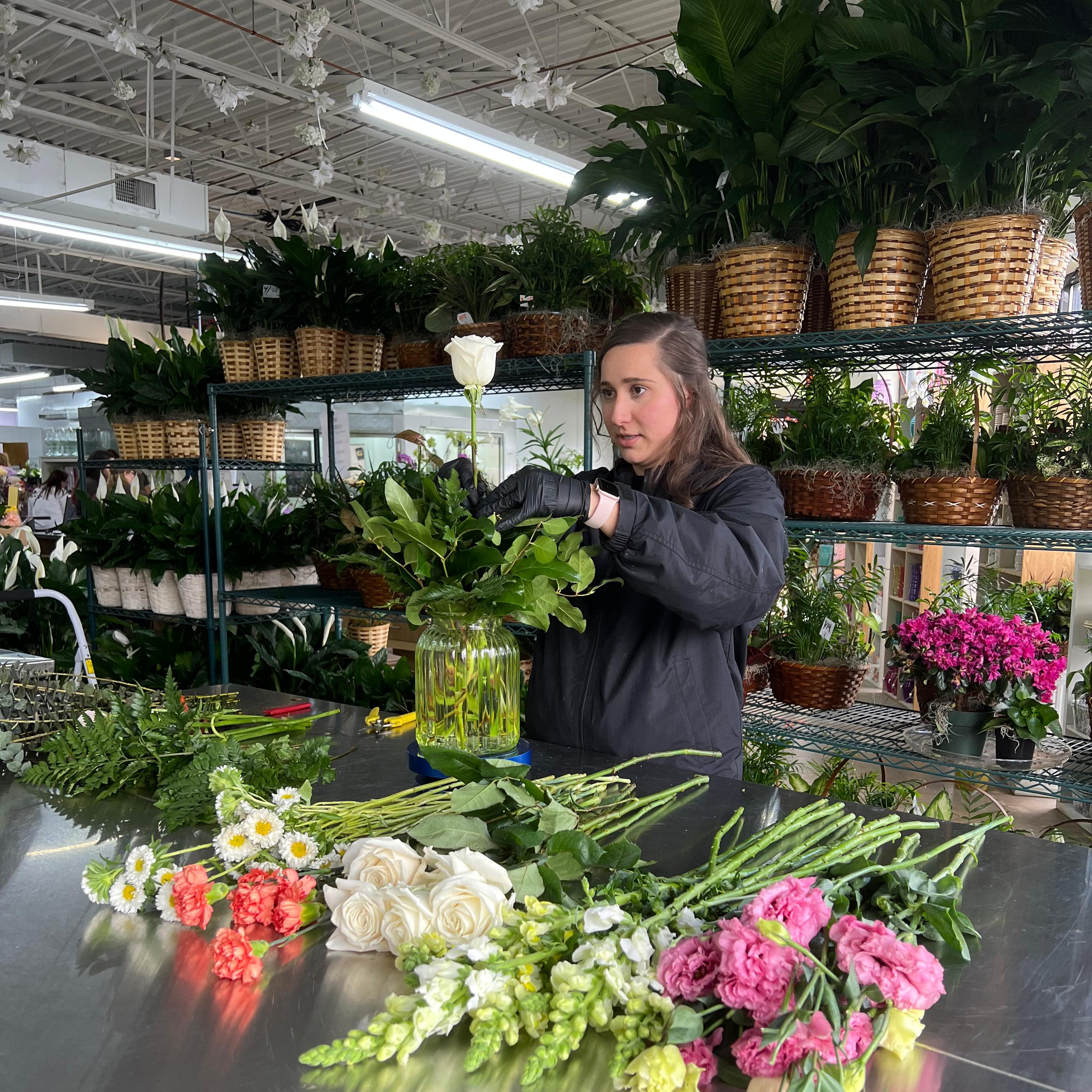 a woman is arranging flowers in a vase on a table .