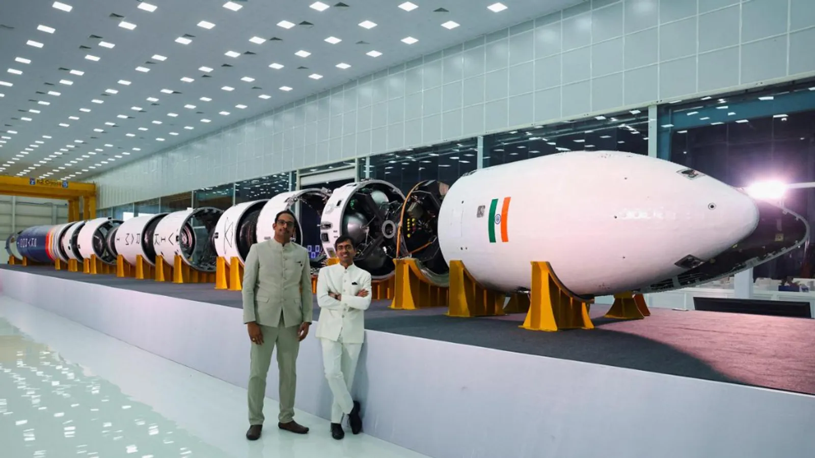 Skyroot founders Pawan Kumar Chandna and Naga Bharath Daka standing in traditional attire in front of Vikram-1 rocket