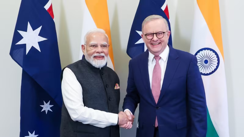 Indian PM Narendra Modi and Australian PM Anthony Albanese shake hands in front of national flags