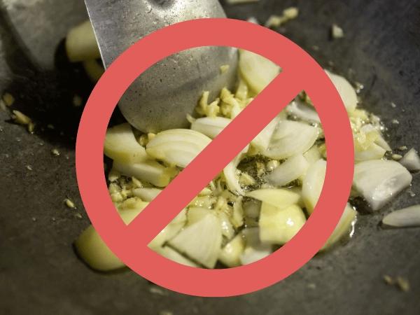 An image of onions and garlic which are toxic food for dogs, overlaid with a prohibition sign to represent that this isn’t safe food for dogs