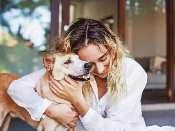 A pet parent hugging her dog after getting emergency vet insurance