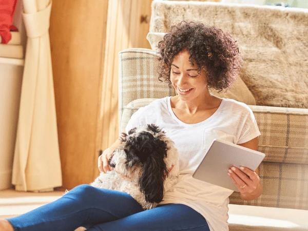 A woman looking at pet insurance for dogs while sitting next to her dog