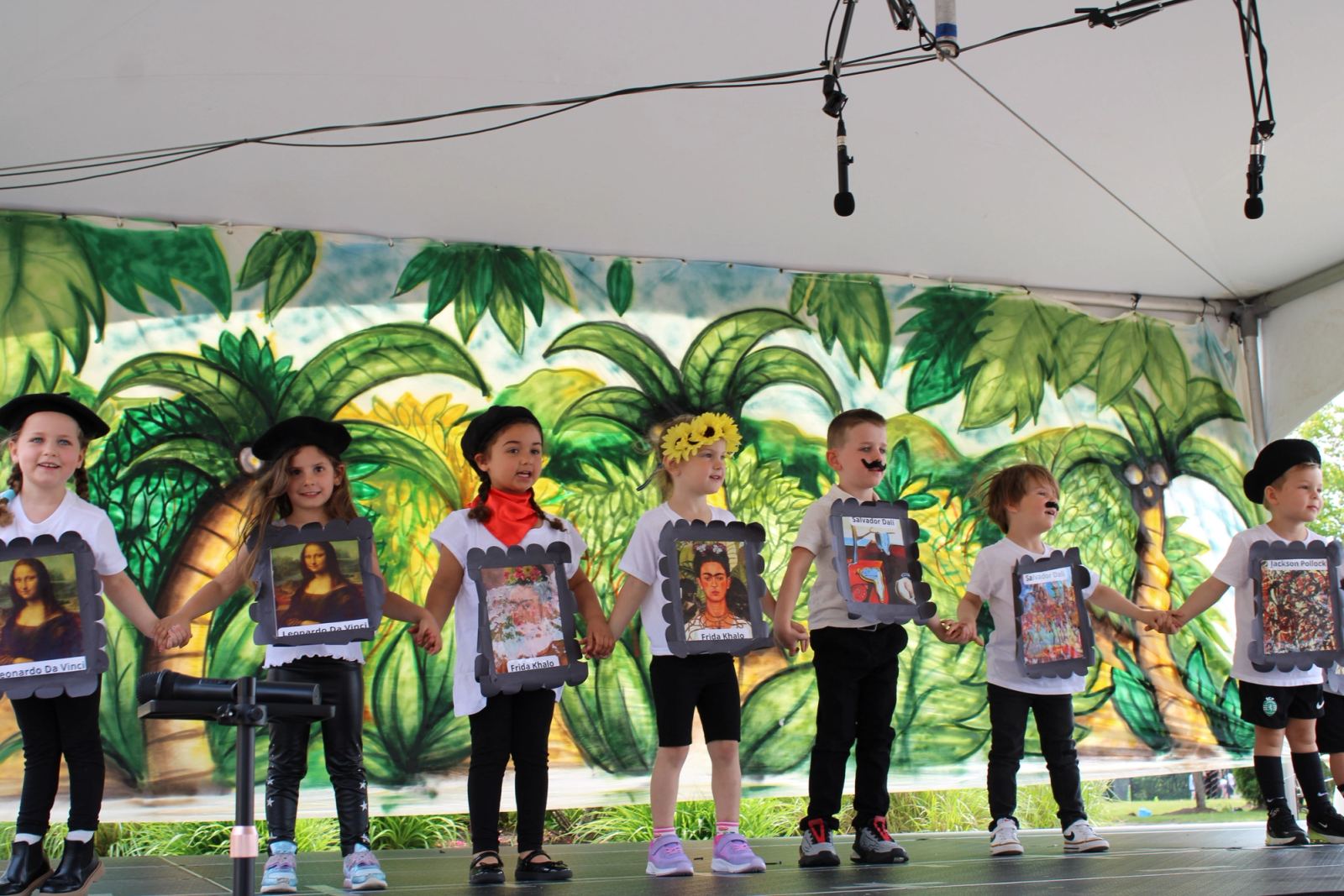 SELA students at our end of year graduation on stage holding hands and showing off famous art