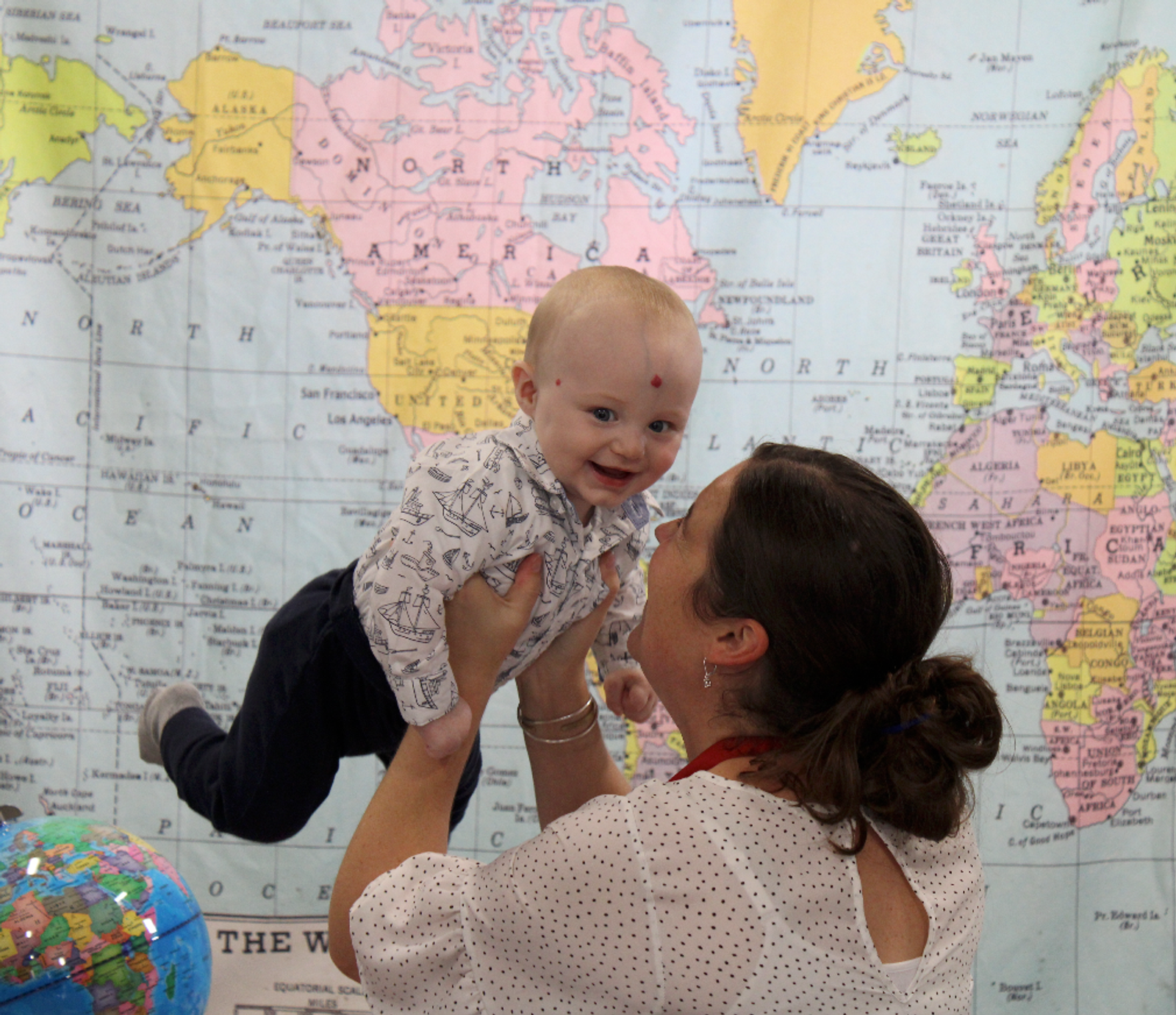 Early Global Education Director holding up a smiling infant on picture day